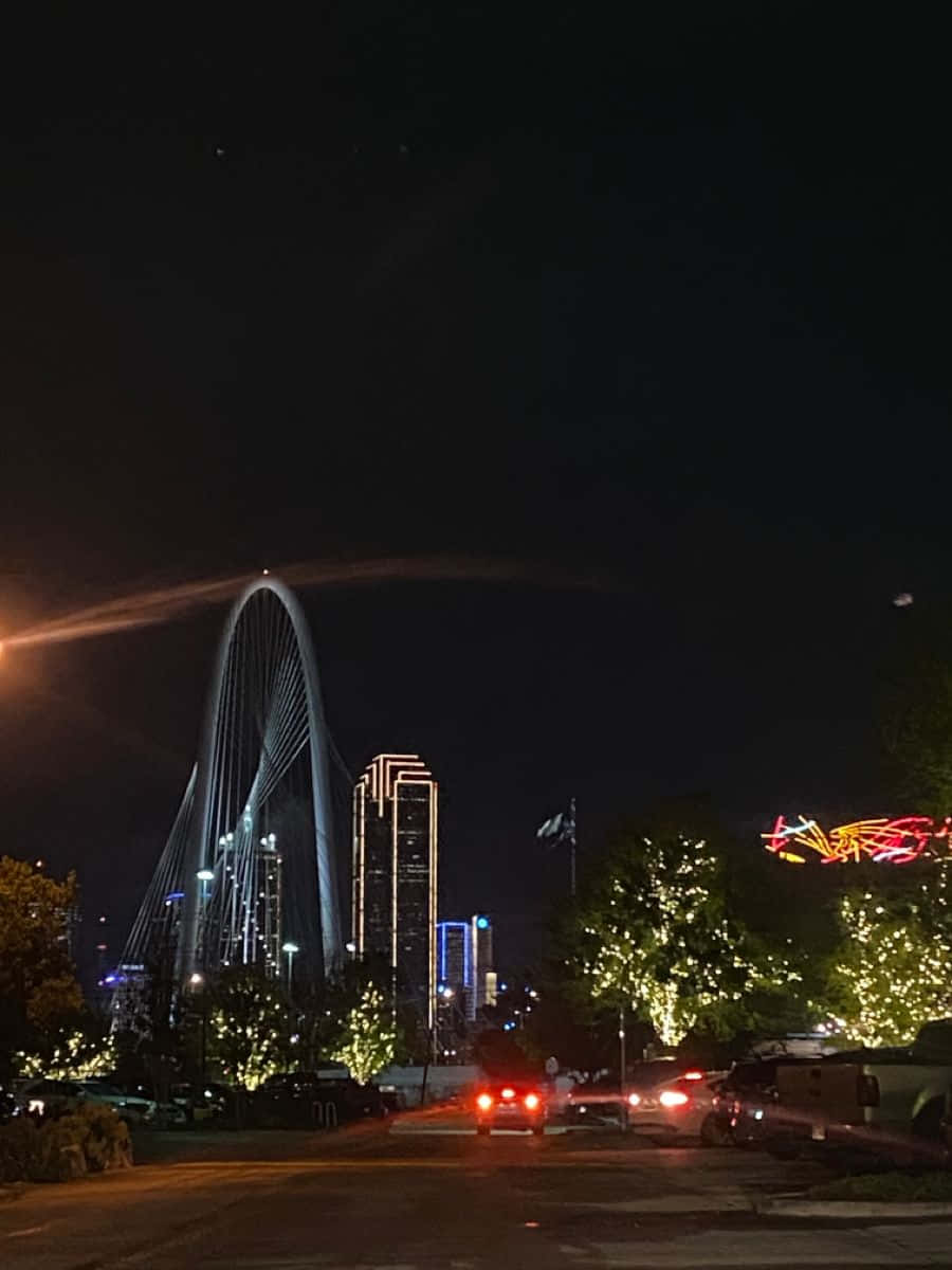 Night Time 桌布 壁紙 — 夜晚城市景觀，有一座發光的拱橋和燈火通明的摩天大樓，樹木和汽車上裝飾著節日燈飾。