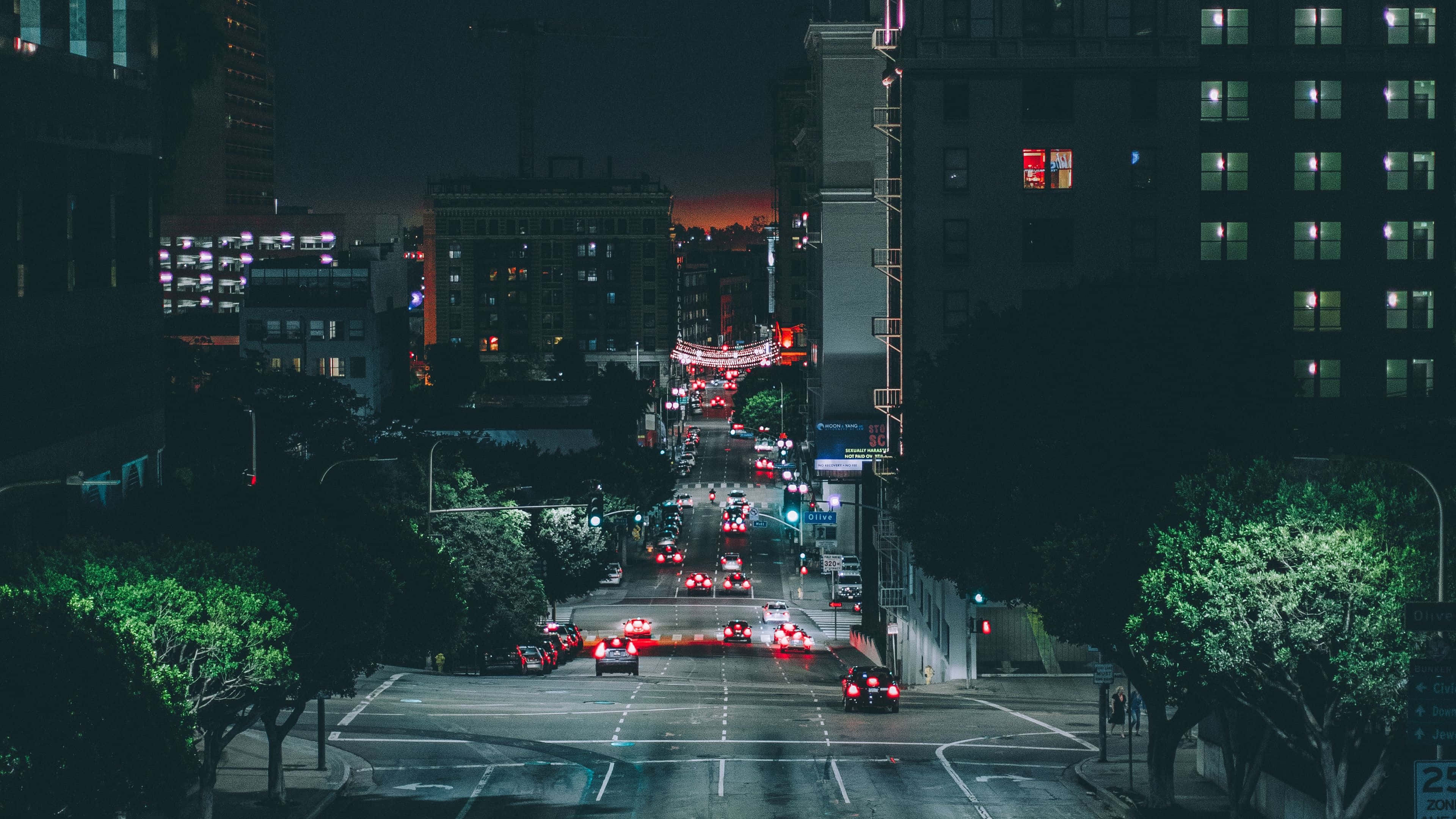 Dark Crossroad 桌布 壁紙 — 夜晚城市街道景觀，發光的汽車尾燈在高樓大廈之間延伸向遠方的橙色地平線。