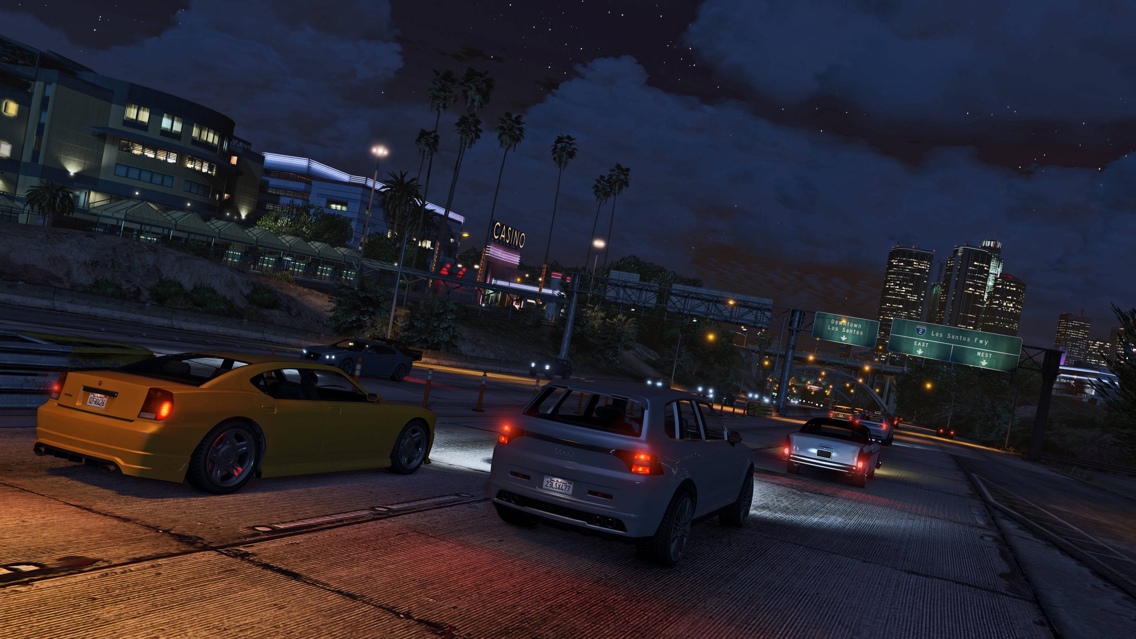 Gta 桌布 壁紙 — 夜晚城市高速公路，有發光的汽車和棕櫚樹，在星空下靠近賭場標誌。