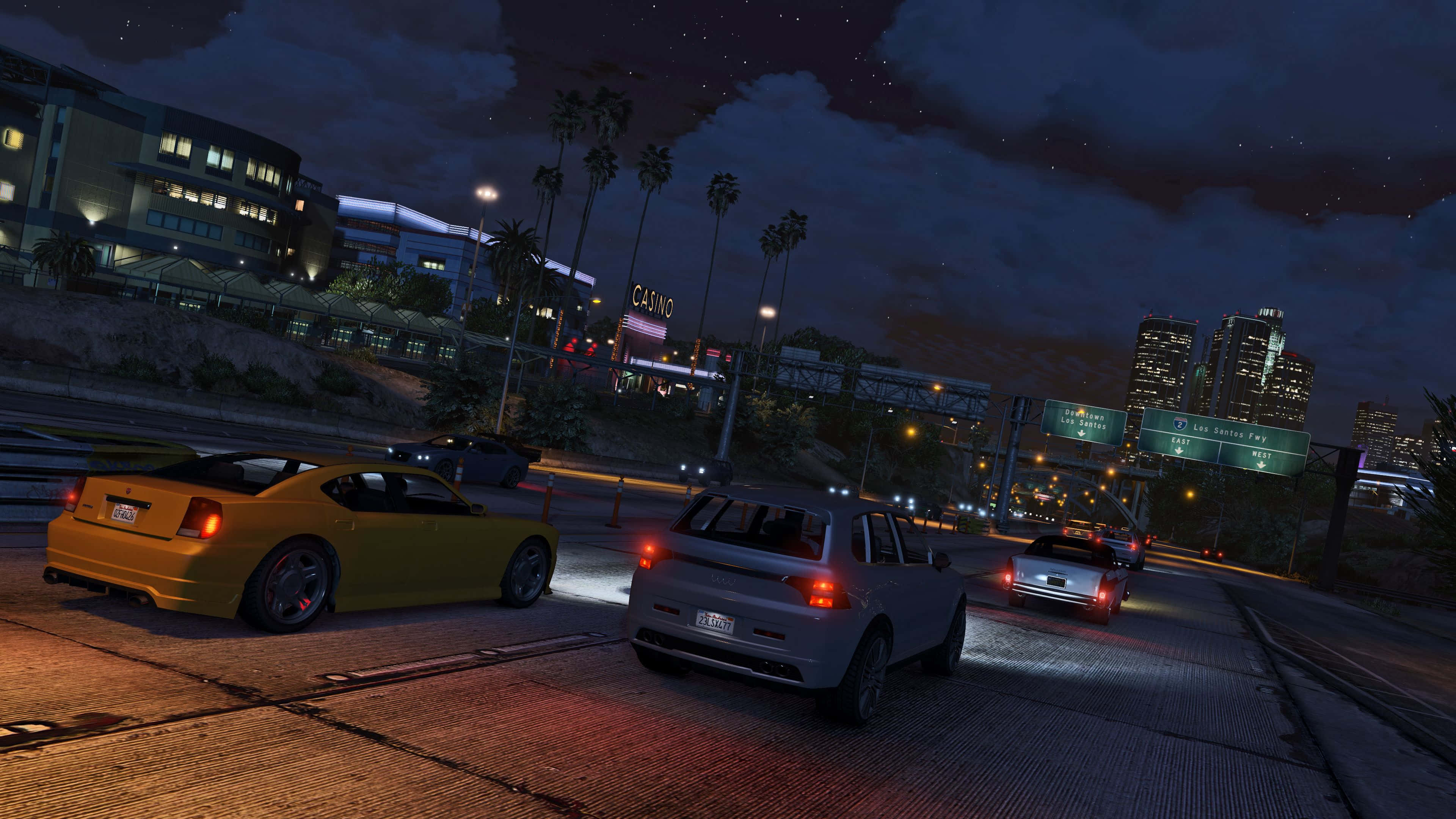 Gta V 4K 桌布 壁紙 — 夜晚城市高速公路，閃爍的汽車和棕櫚樹，星空下遠處的賭場燈光。