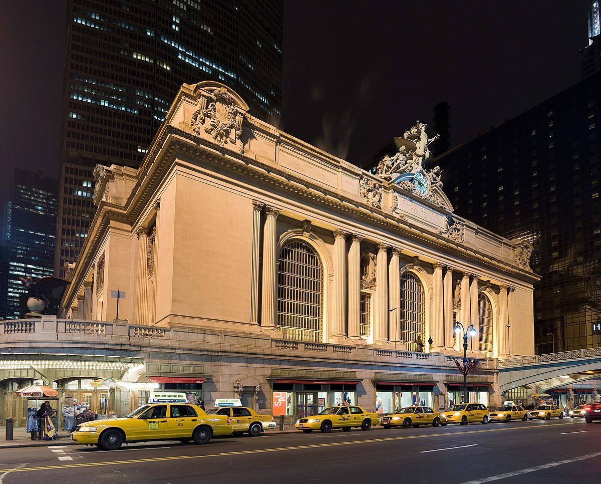 New York 桌布 壁紙 — 夜晚宏偉的Beaux-Arts火車站，街道旁有黃色計程車，背景是高聳的摩天大樓。