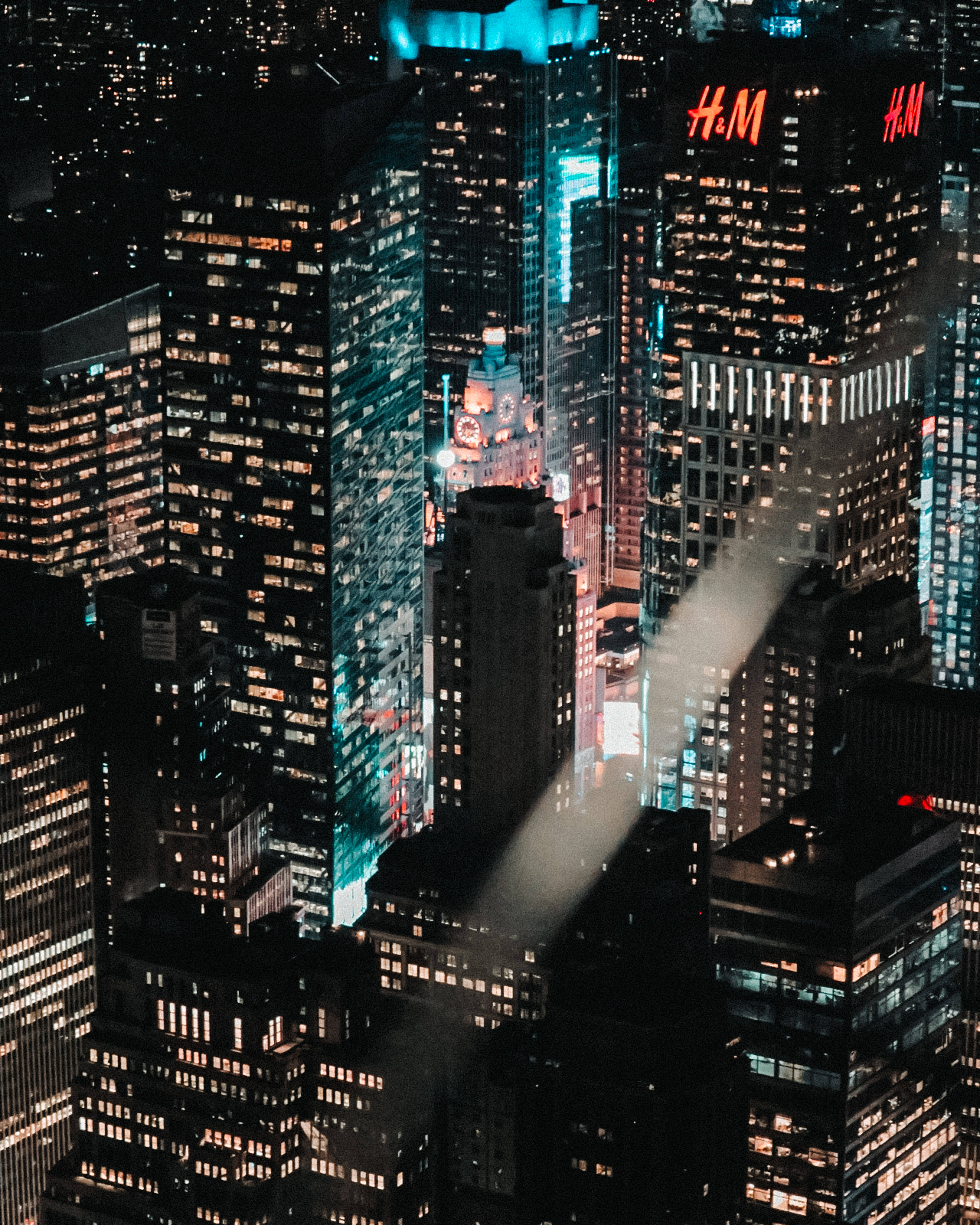 Skyscraper 桌布 壁紙 — 夜晚密集城市景觀的鳥瞰圖，高聳的摩天大樓閃爍著溫暖和冷色調的光芒。