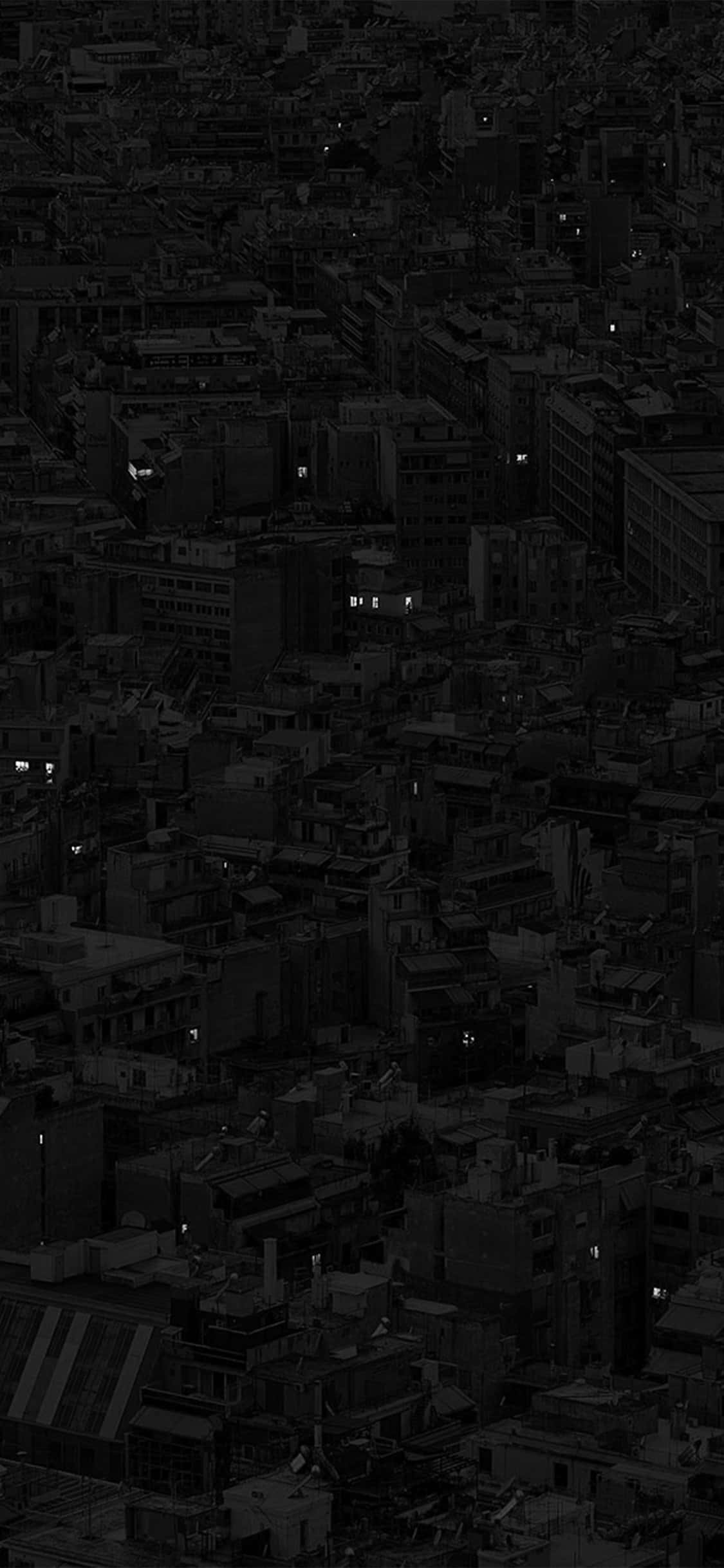 深色 iPhone 桌布 壁紙 — 夜晚密集城市的鳥瞰圖，散落的發光窗戶穿透黑暗的城市擴展區。