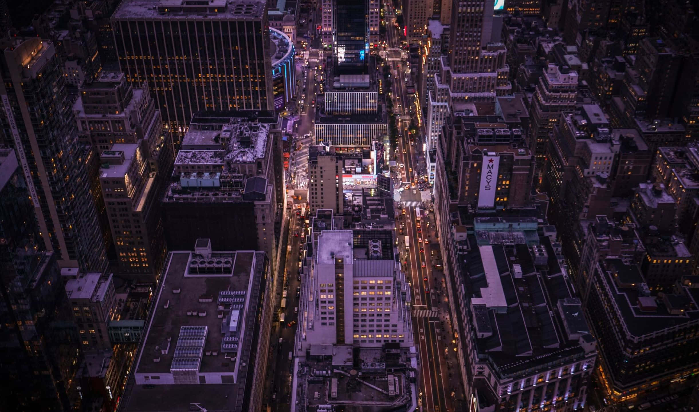 2440x1440 Empire State Building 桌布 壁紙 — 夜晚密集城市的鳥瞰圖，有發光的街燈和照亮的高樓大廈。