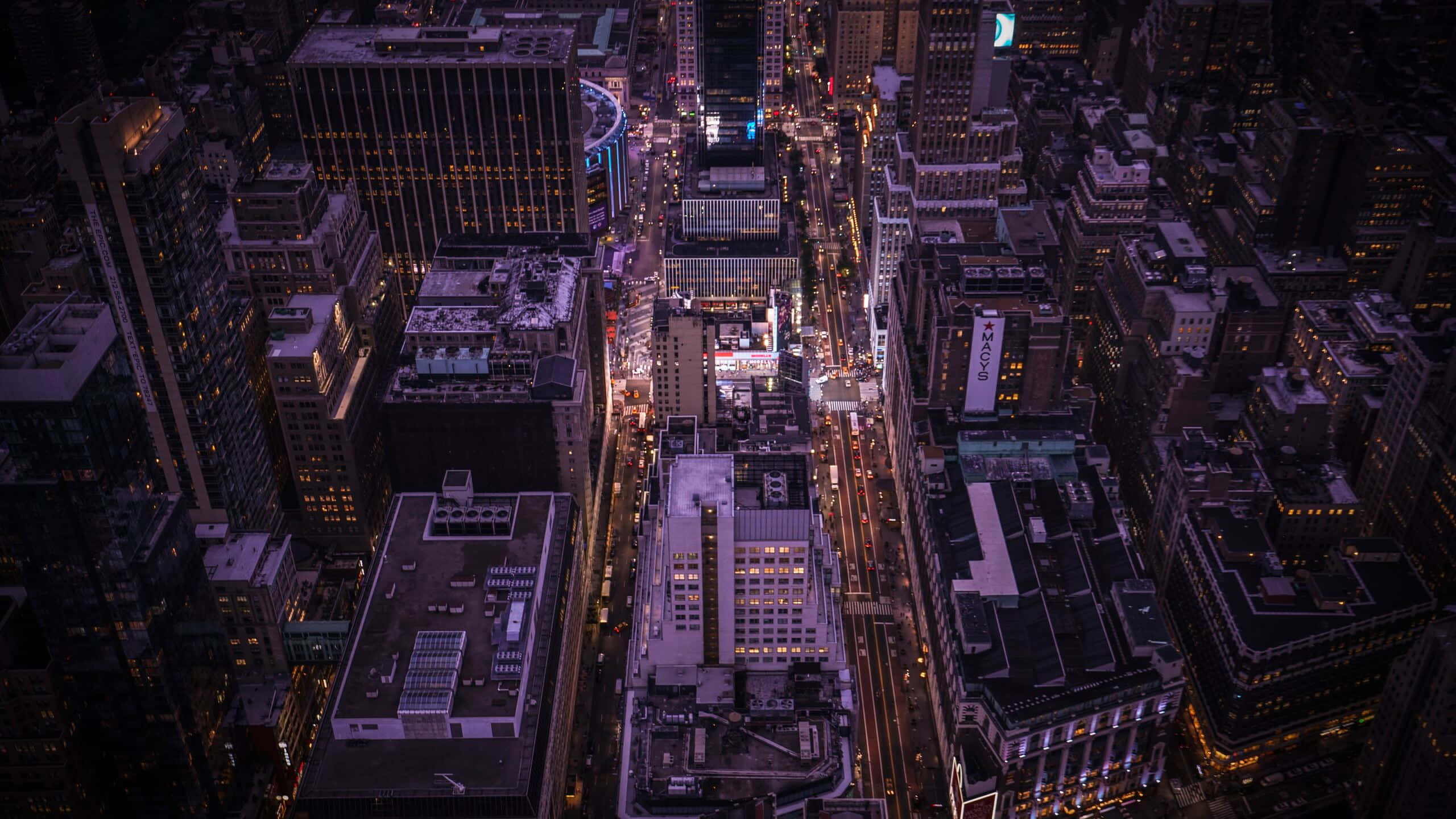 Top View 桌布 壁紙 — 夜晚密集城市的鳥瞰圖，有發光的街燈和亮燈的摩天大樓。