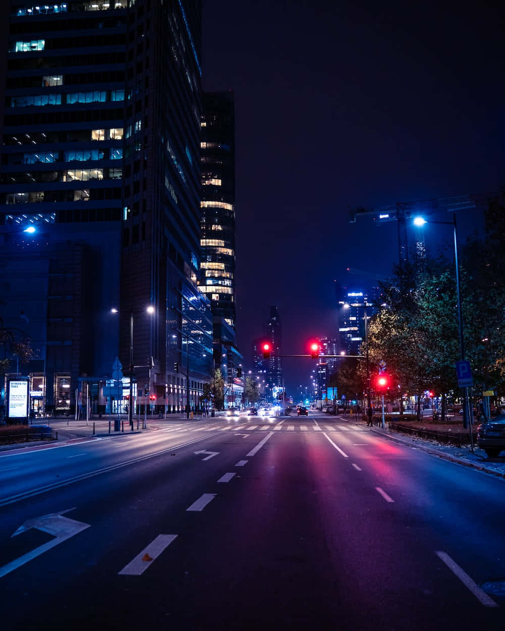 夜晚 桌布 壁紙 — 夜晚寧靜的城市街道，高樓在街燈下發光，紅色交通信號燈在潮濕的路面上投射出倒影。