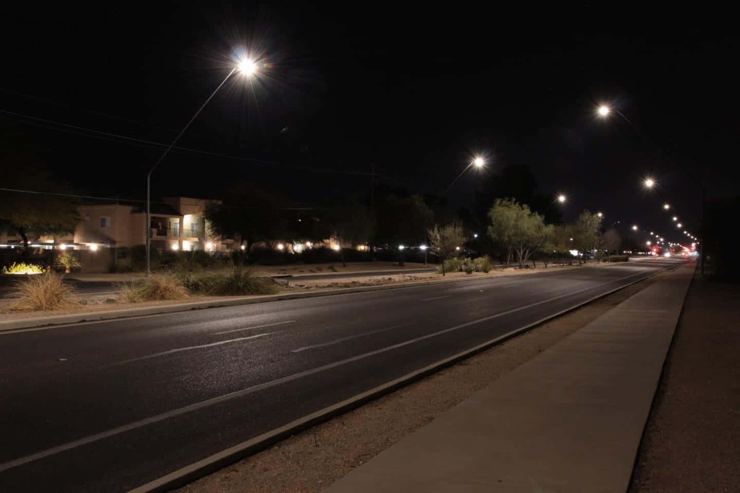 Night Time 桌布 壁紙 — 夜晚寧靜的郊區街道，路燈在瀝青上投下長長的影子。