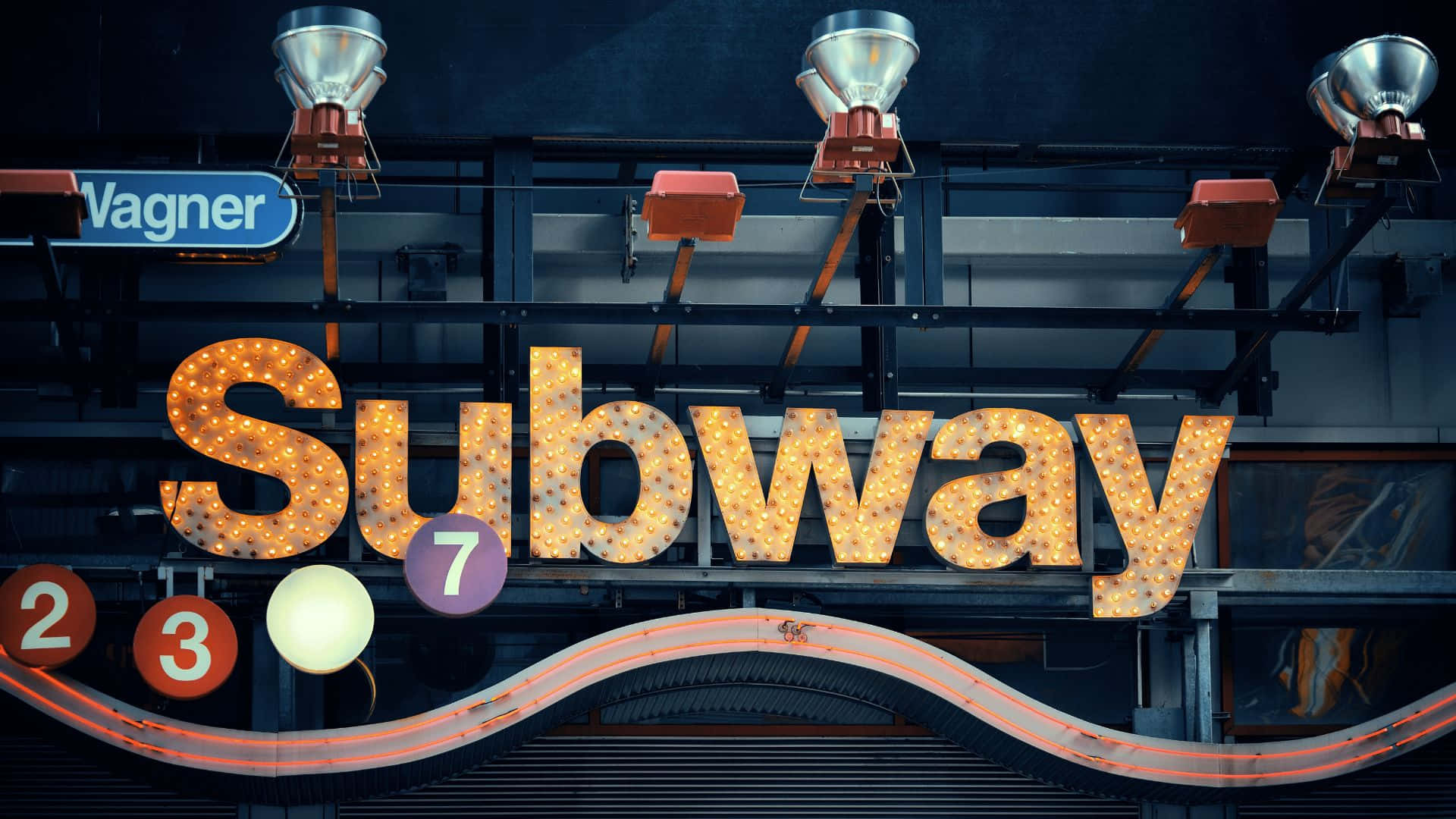 Subway 桌布 壁紙 — 夜晚工業燈光下，一個發光的地鐵標誌，帶有發光字母和路線編號。