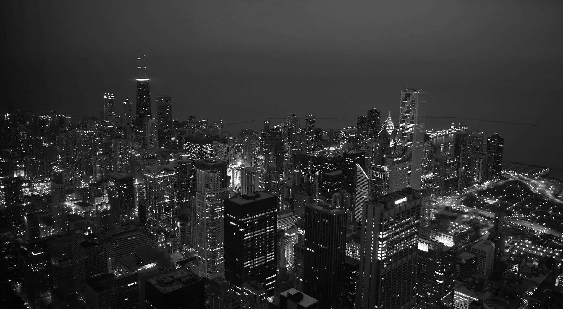 Aesthetic Black 桌布 壁紙 — 夜晚廣闊城市景觀的單色航拍圖，高樓大廈燈火通明，街道閃爍。