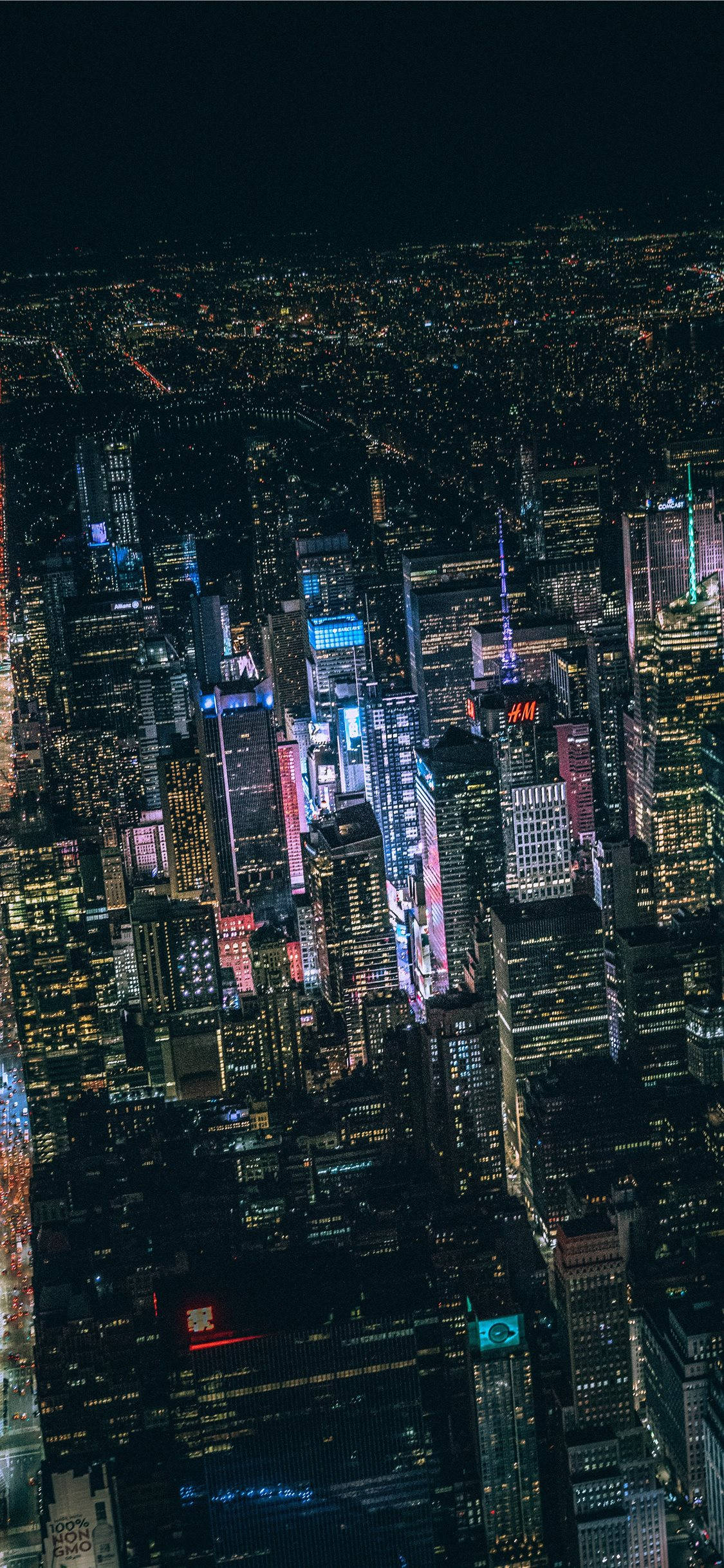 桌布 壁紙 — 夜晚廣闊城市景觀的鳥瞰圖，無數發光的窗戶和充滿活力的霓虹燈照亮了高聳的摩天大樓。