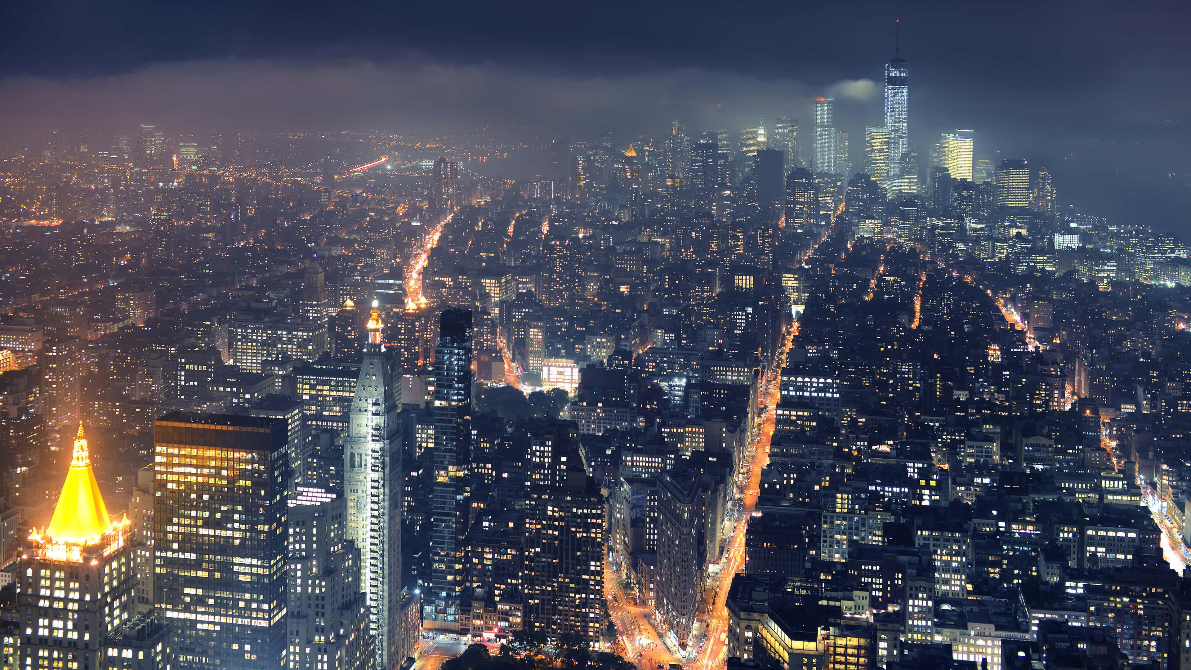 New York City 4K Ultra HD 桌布 壁紙 — 夜晚廣闊城市的鳥瞰圖，在陰暗多雲的天空下，閃爍的摩天大樓和燈火通明的街道。