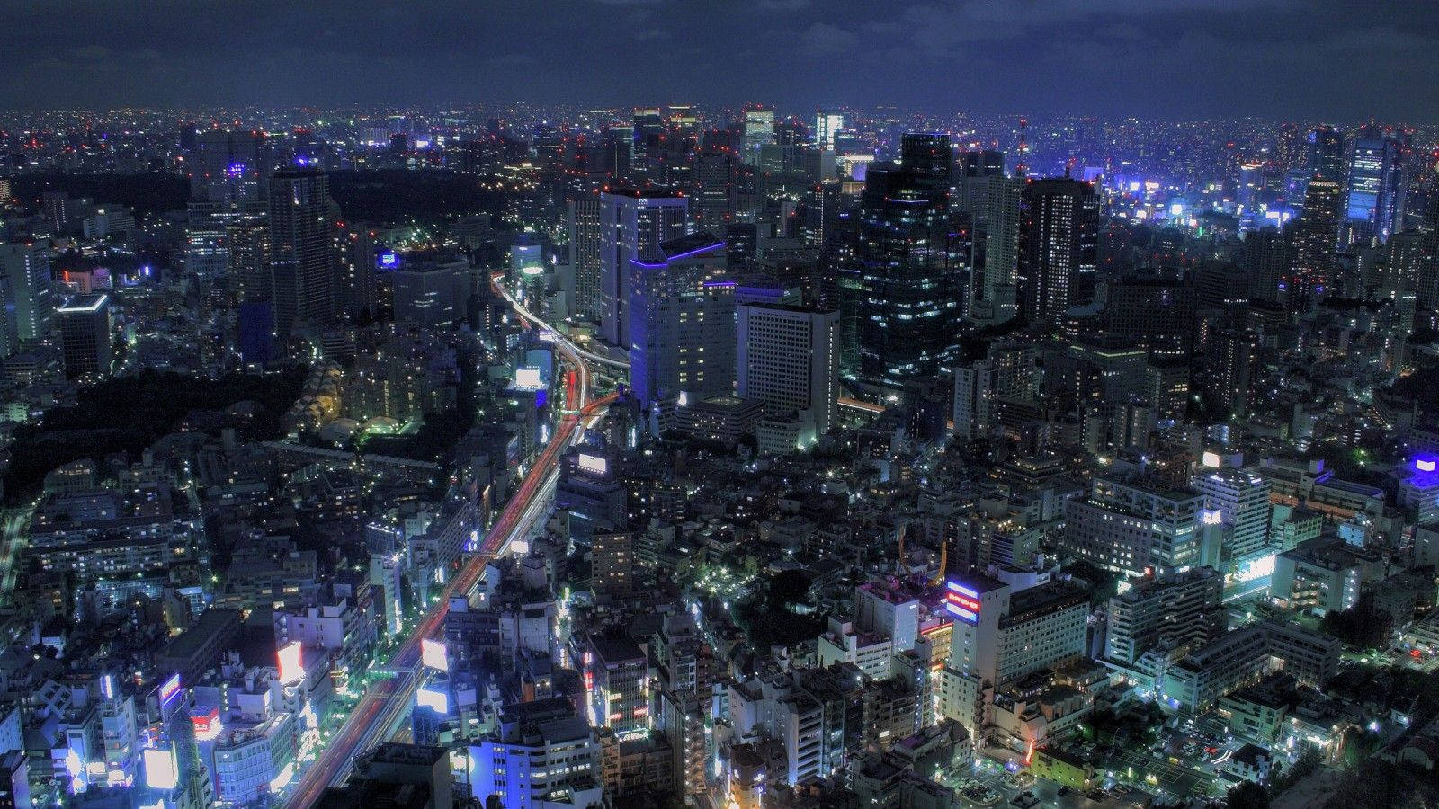 日本 桌布 壁紙 — 夜晚廣闊城市的鳥瞰圖，閃爍的摩天大樓和交通燈光軌跡。
