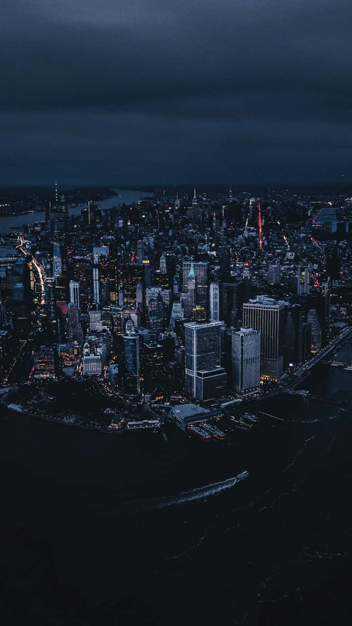 美學 桌布 壁紙 — 夜晚廣闊城市的鳥瞰圖，閃爍的摩天大樓和黑暗的水面在暴風雨的天空下。