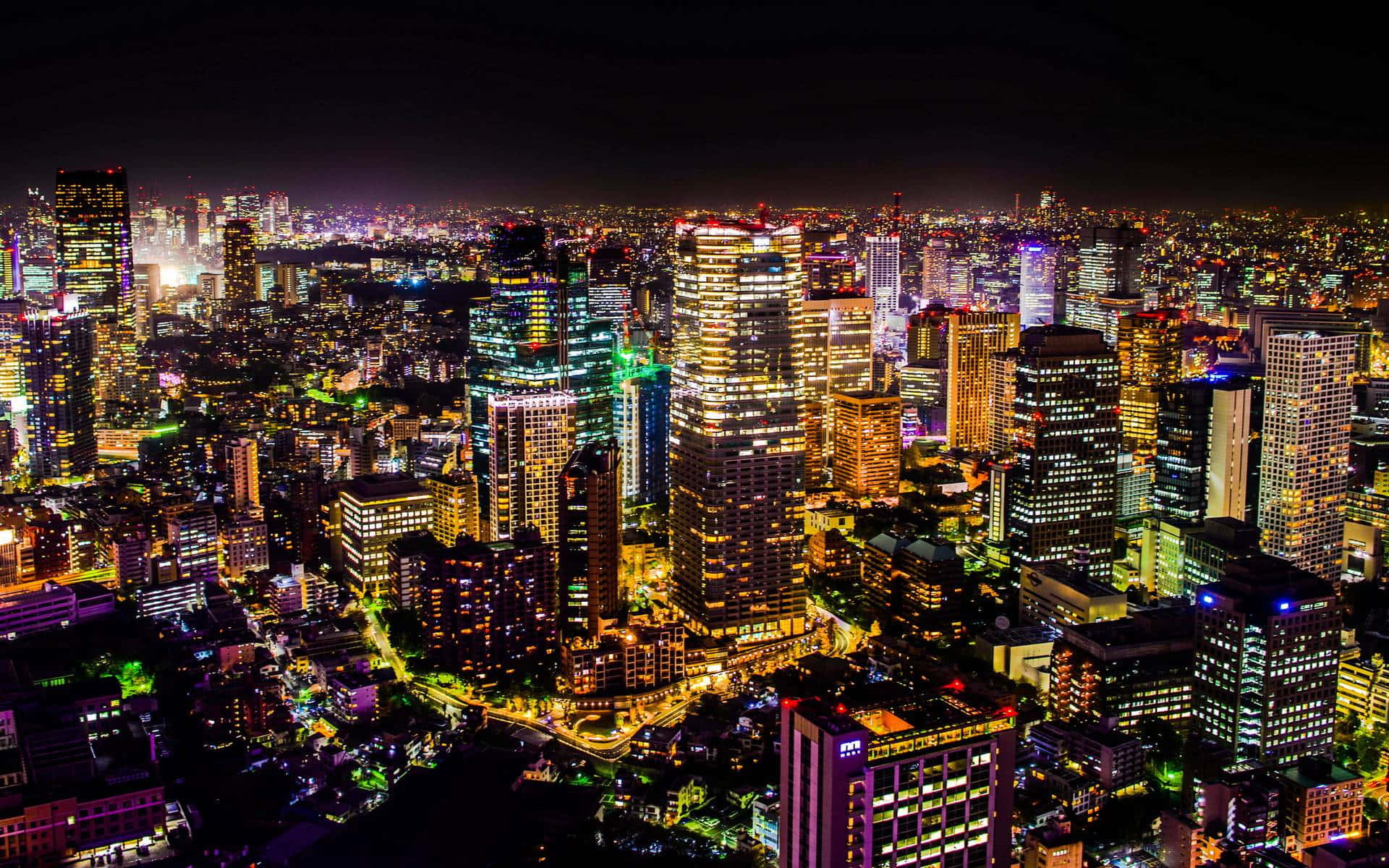 東京 桌布 壁紙 — 夜晚廣闊城市的鳥瞰圖，高聳的摩天大樓在黑暗的天空中閃爍著五彩繽紛的燈光。