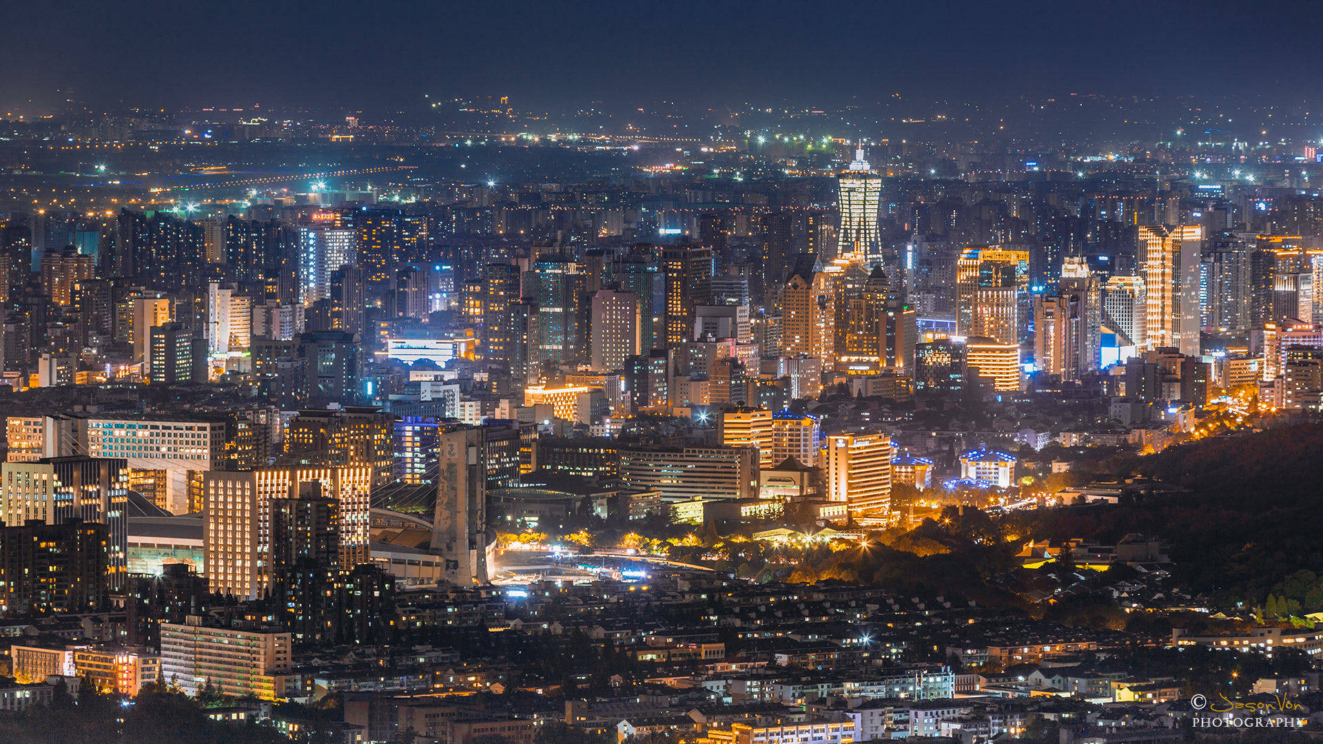 Hangzhou 桌布 壁紙 — 夜晚廣闊的城市景觀，無數發光的窗戶和燈火通明的摩天大樓延伸至遠方。