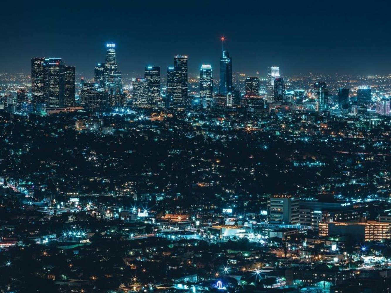lights 桌布 壁紙 — 夜晚廣闊的城市景觀，高聳的摩天大樓和閃爍的燈光延伸至遠方。