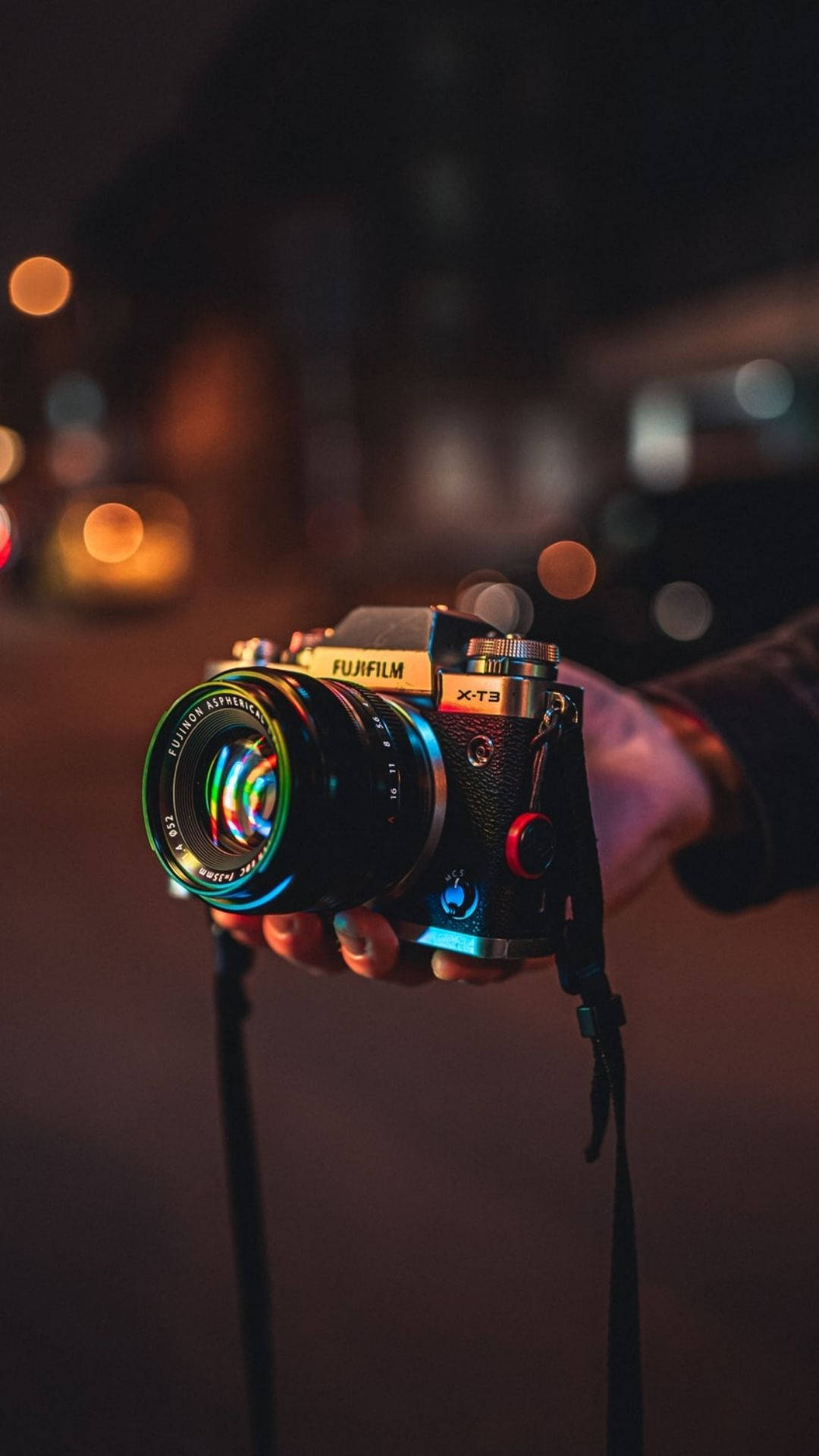 夜晚手持Fujifilm X-T3相機，帶有發光的散景燈光。