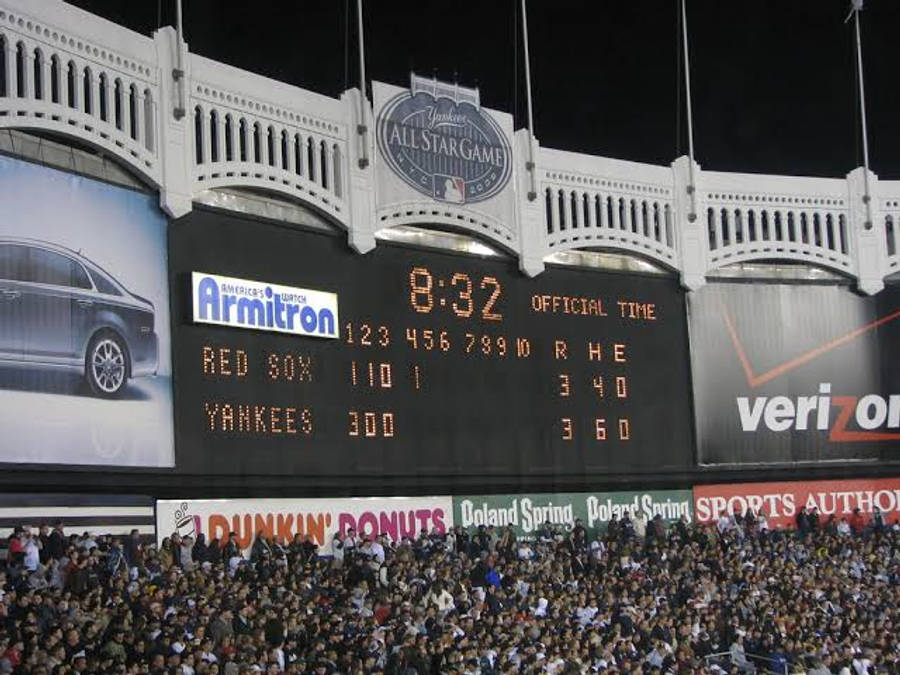 Red Sox 桌布 壁紙 — 夜晚擠滿人的棒球場，巨型記分板顯示洋基隊對紅襪隊的比分和Armitron汽車廣告。