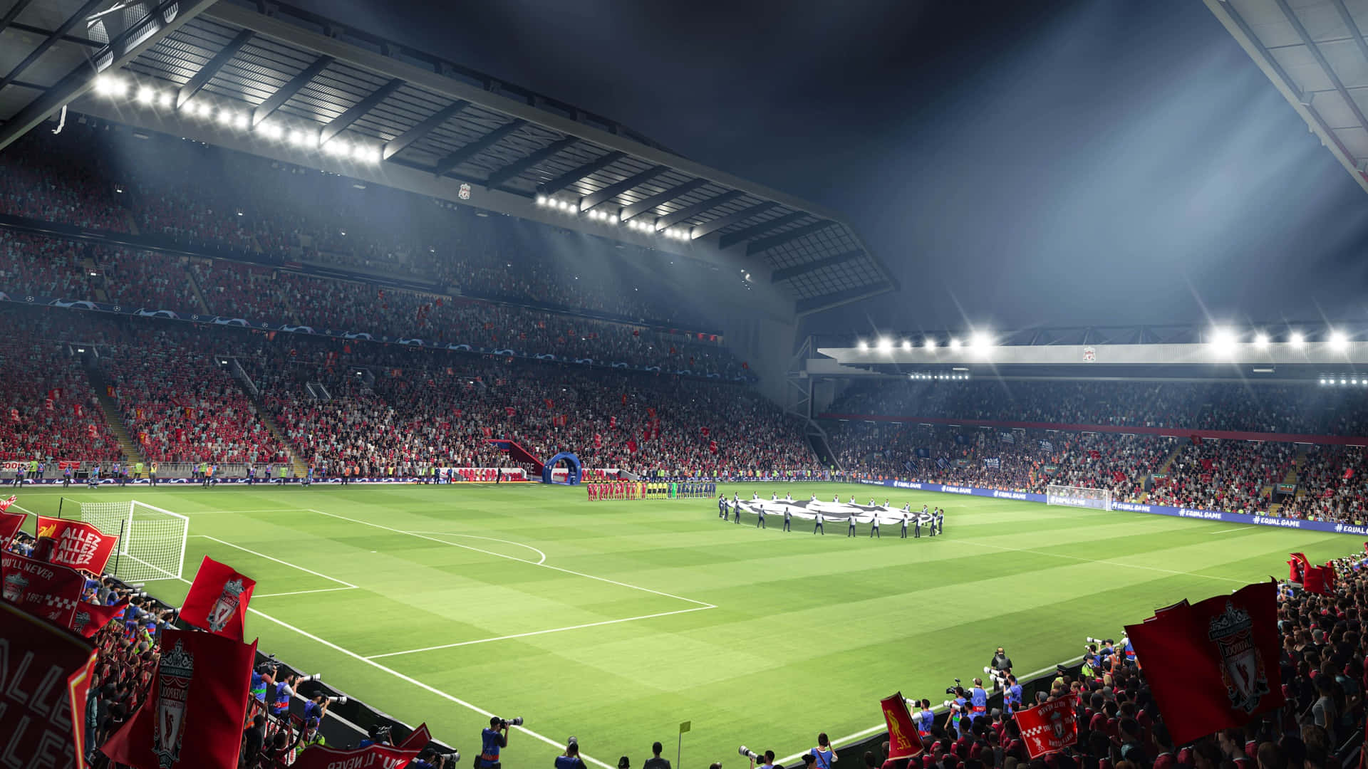 Fifa 22 桌布 壁紙 — 夜晚擠滿人的足球場，球迷揮舞紅旗，球員在明亮的泛光燈下在球場上列隊。