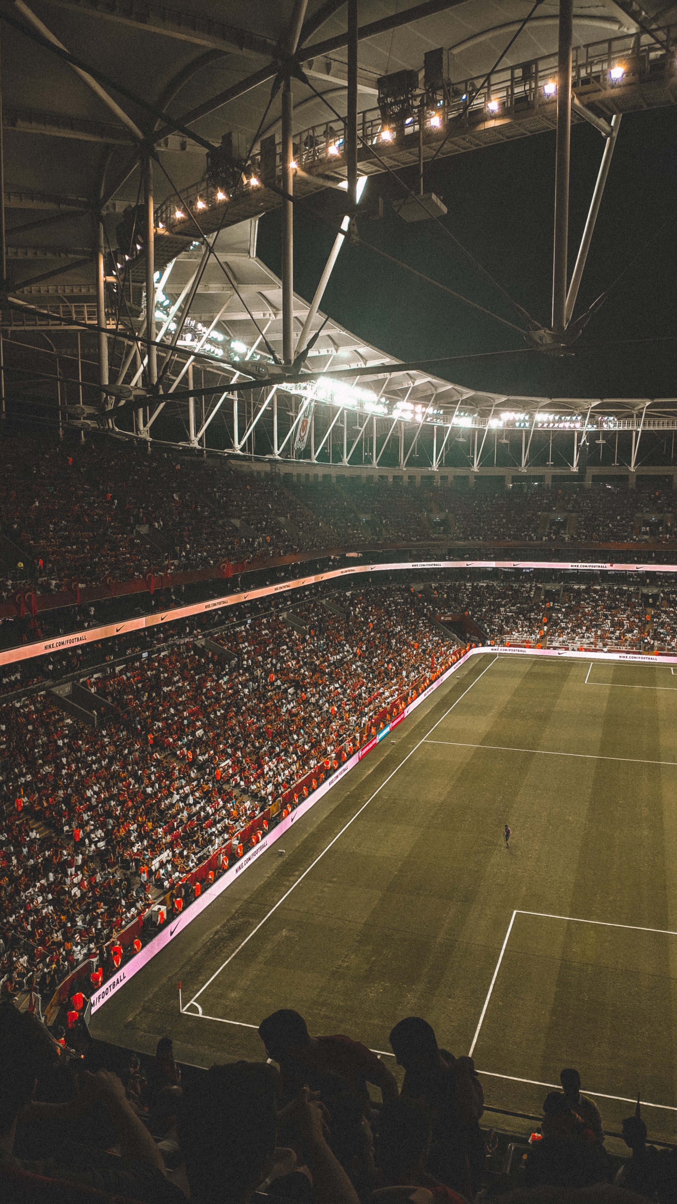 Football Field 桌布 壁紙 — 夜晚擠滿觀眾的體育場，被明亮的燈光照亮，場上只有一名球員。