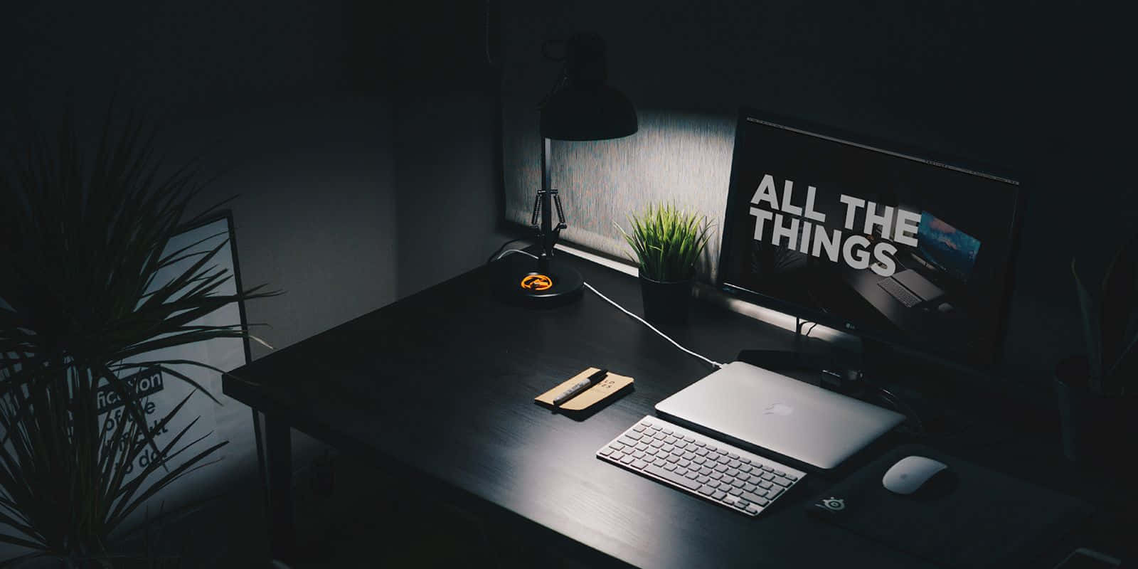 筆電 桌布 壁紙 — 夜晚昏暗的現代書桌，發光的顯示器顯示 'ALL THE THINGS'，以及聚焦燈光下的筆記型電腦鍵盤。