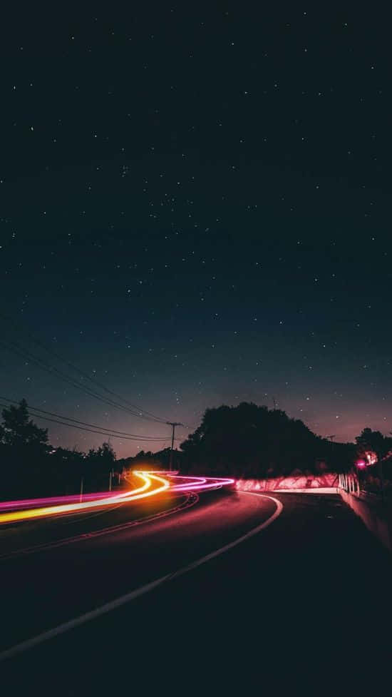 Night Time 桌布 壁紙 — 夜晚星空下蜿蜒的道路，伴隨著過往車輛留下的鮮豔光軌。