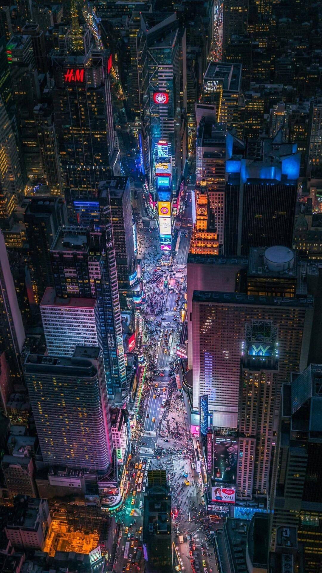 Skyscraper 桌布 壁紙 — 夜晚時代廣場的鳥瞰圖，高聳的摩天大樓閃爍著鮮豔的霓虹燈招牌，下方是繁華的街道。