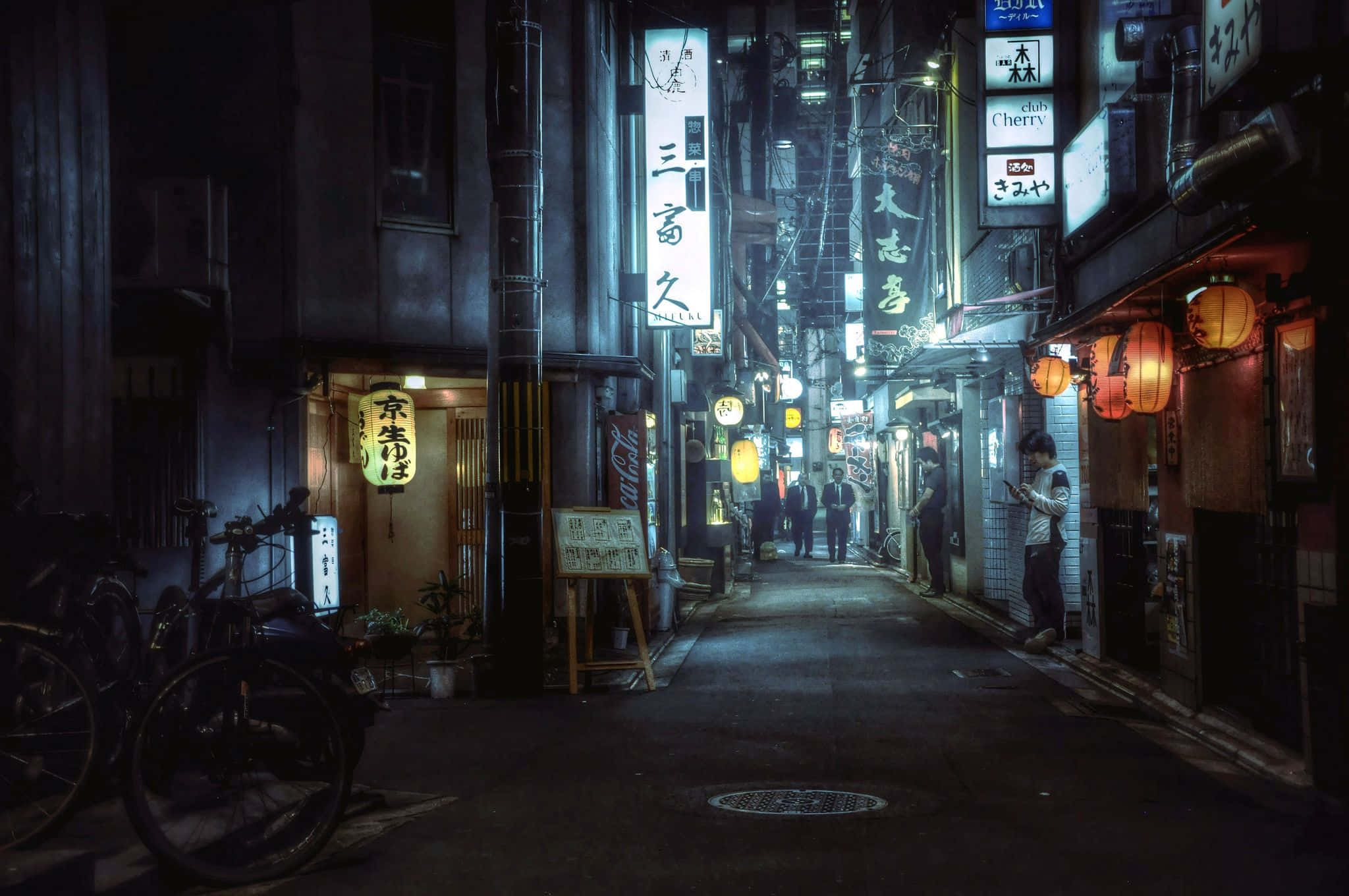 Alleyway 桌布 壁紙 — 夜晚東京一條狹窄小巷，被發光的霓虹招牌和紙燈籠照亮，在潮濕的路面上投下溫暖的光芒。