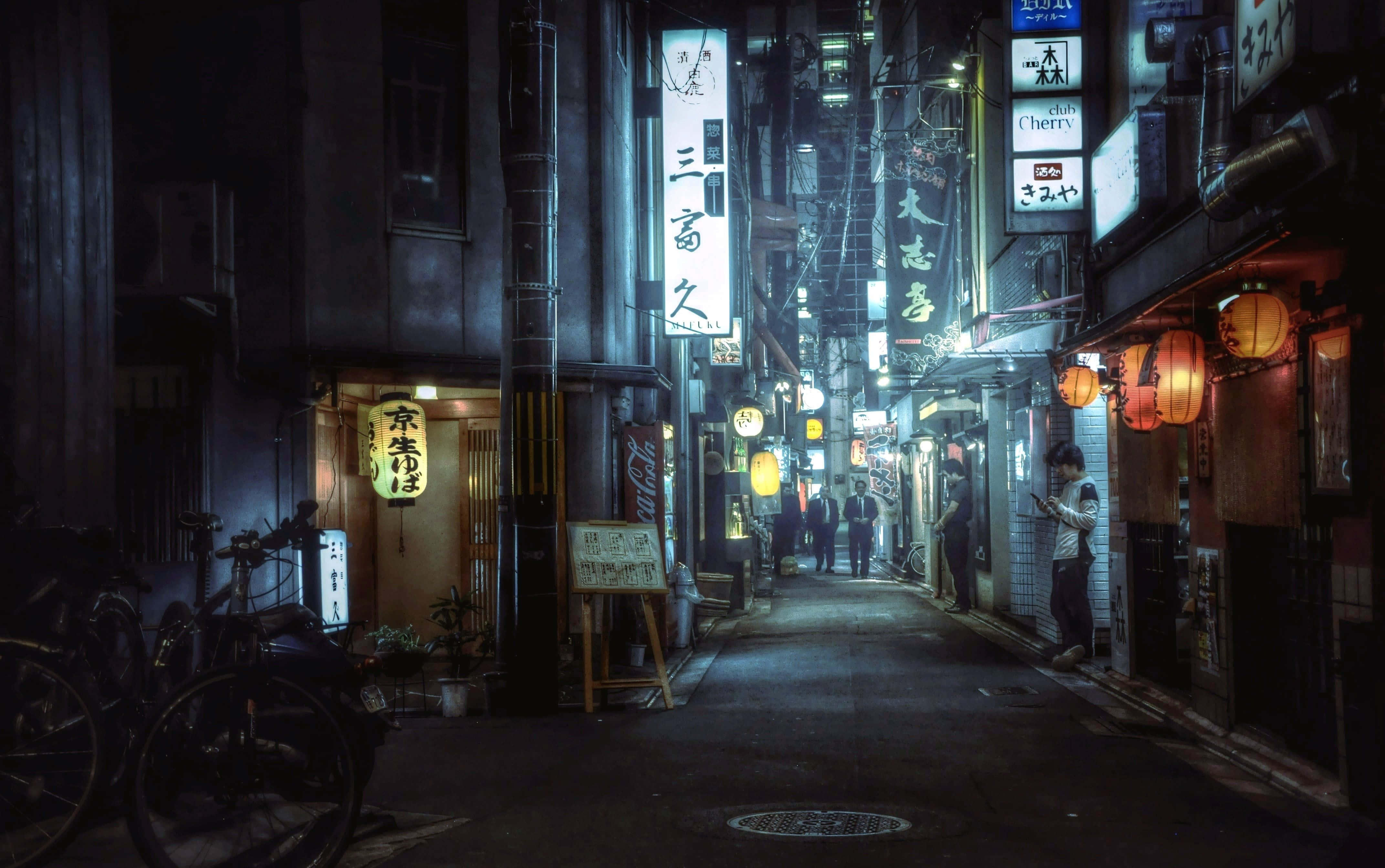 日式審美桌面 桌布 壁紙 — 夜晚東京一條狹窄小巷，被發光的霓虹招牌和紙燈籠照亮，在潮濕的路面上投下溫暖的光芒。