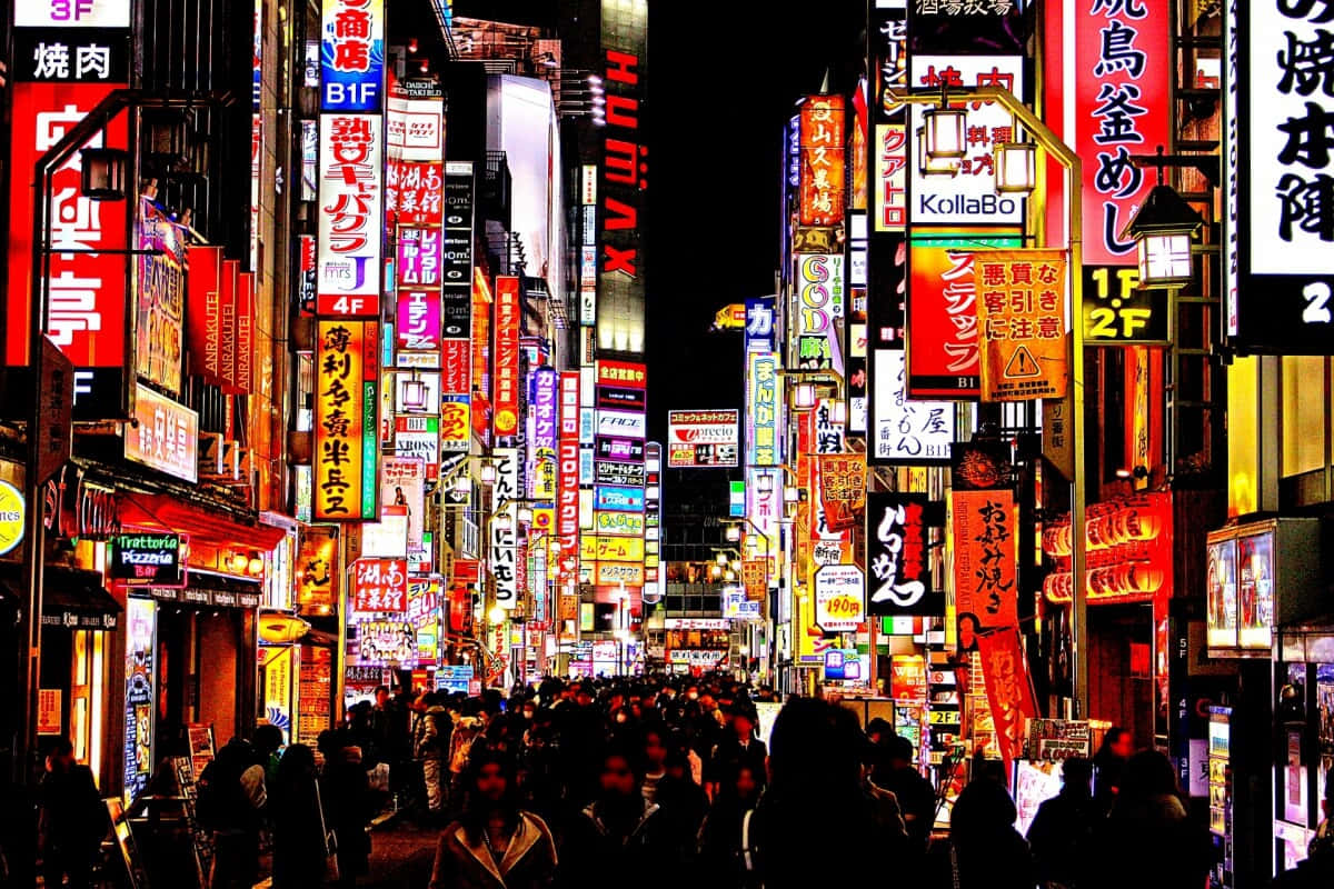 Tokyo Japan 桌布 壁紙 — 夜晚東京一條繁忙的霓虹燈街道，高聳的建築物和發光的招牌倒映在濕漉漉的人行道上。