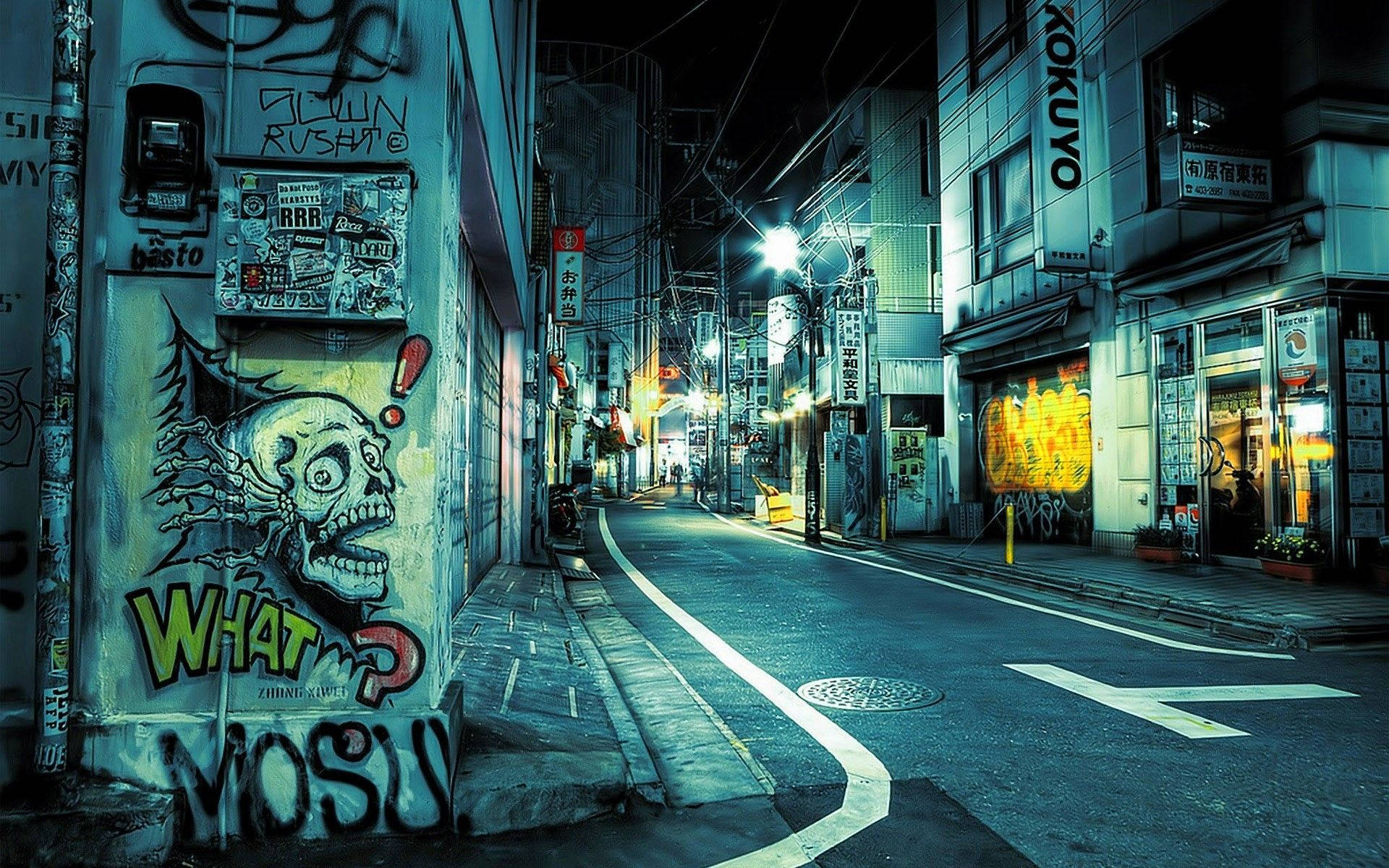 東京 桌布 壁紙 — 夜晚東京一條霓虹燈照亮的後巷，牆上佈滿塗鴉，街燈下骷髏壁畫閃閃發光。