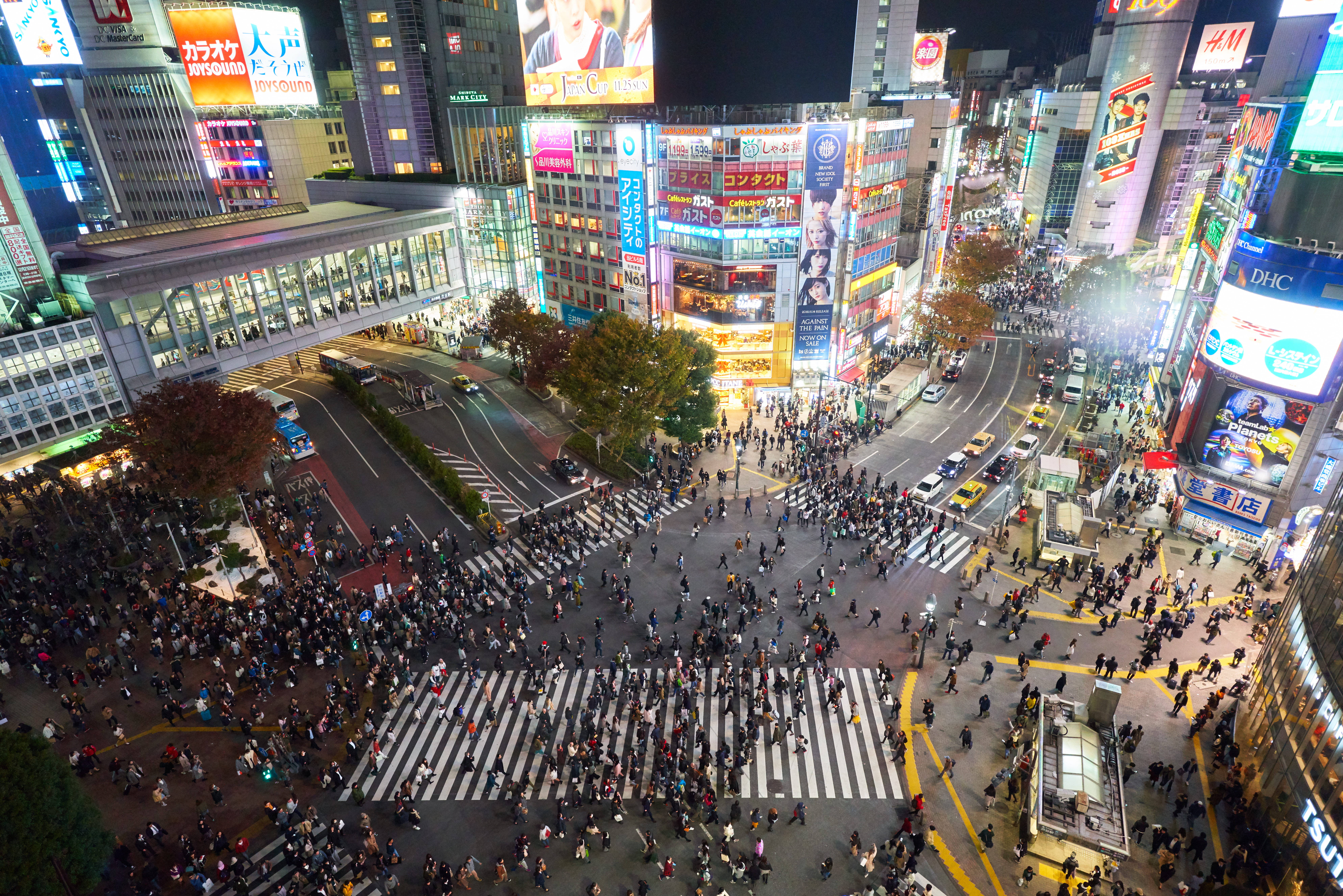 日本 桌布 壁紙 — 夜晚東京繁忙十字路口的鳥瞰圖，有發光的霓虹燈招牌和過馬路的人群。