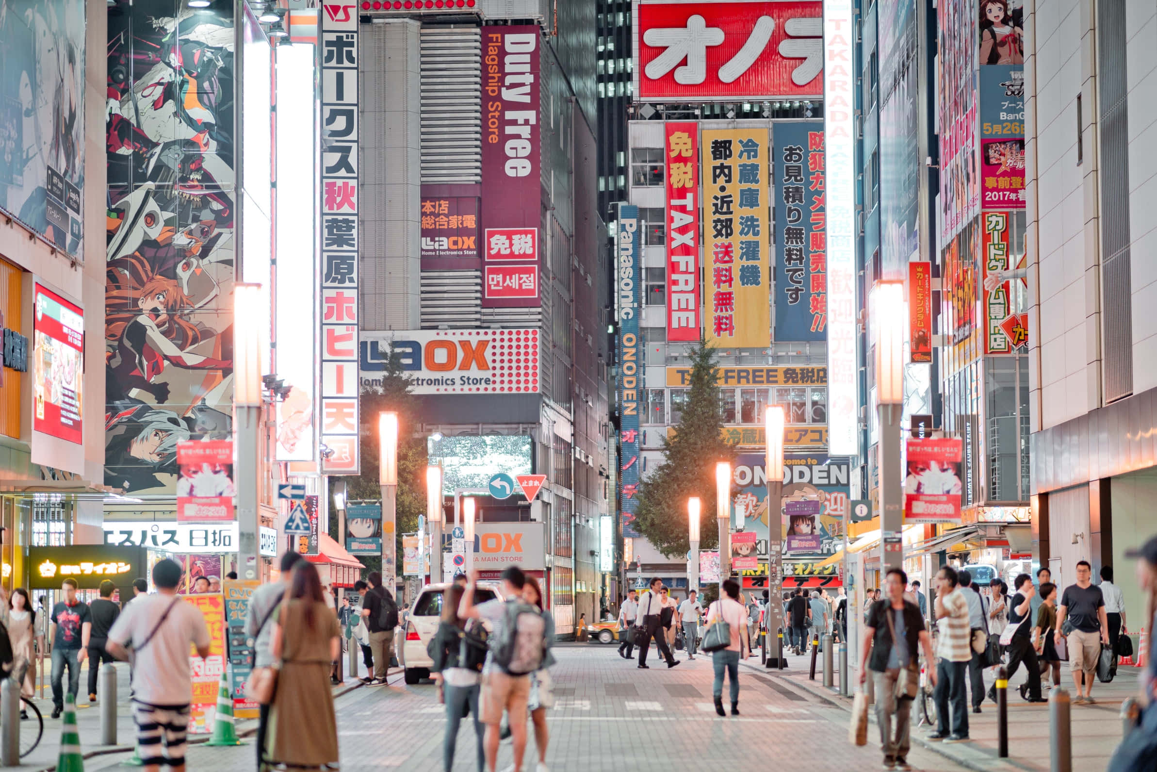 Otaku Culture 桌布 壁紙 — 夜晚東京繁華的街道，霓虹燈牌、動漫廣告看板，人群在燈光下行走。