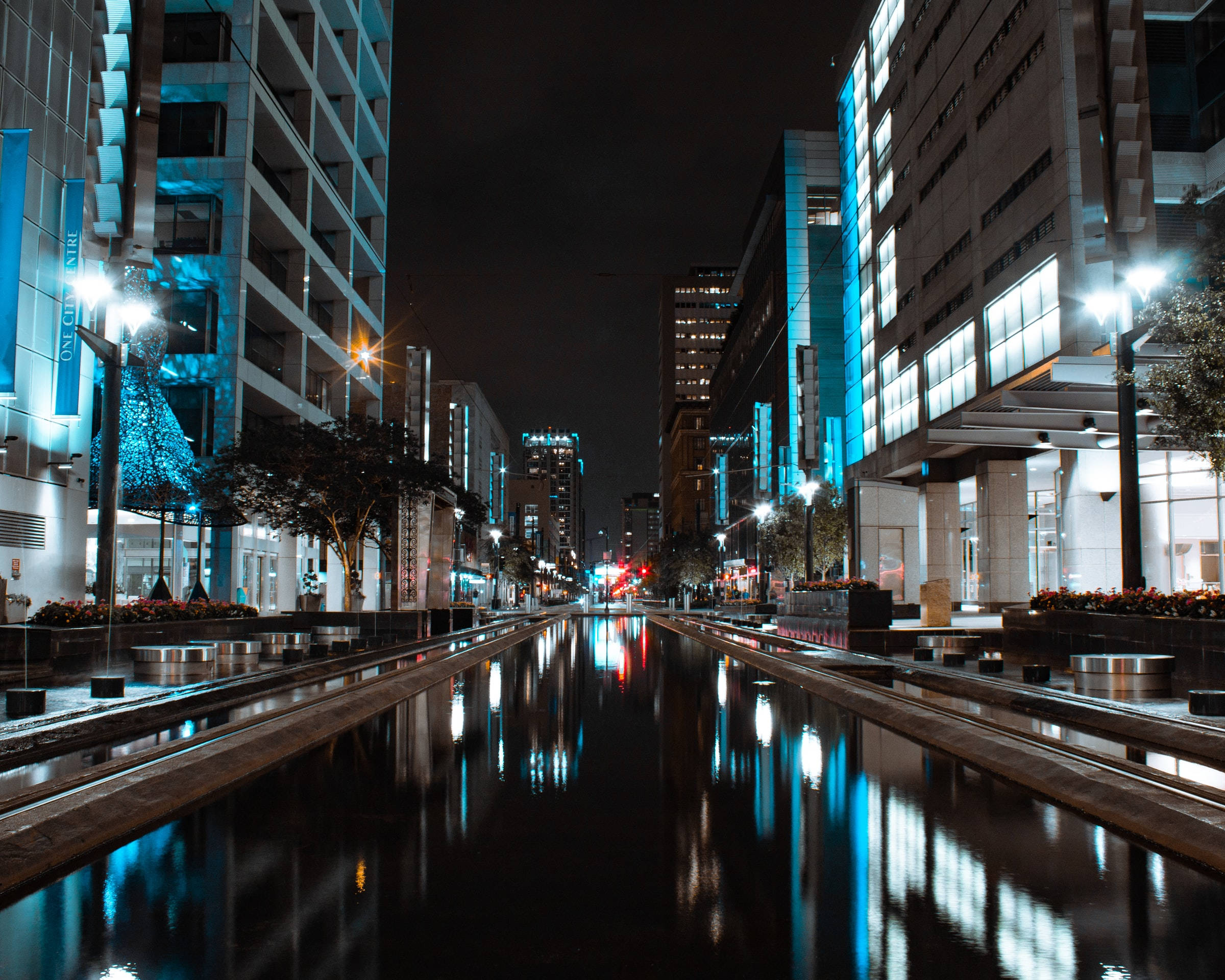 Houston 桌布 壁紙 — 夜晚潮濕的城市運河反射出高聳建築物和街燈發出的藍色和白色光芒。