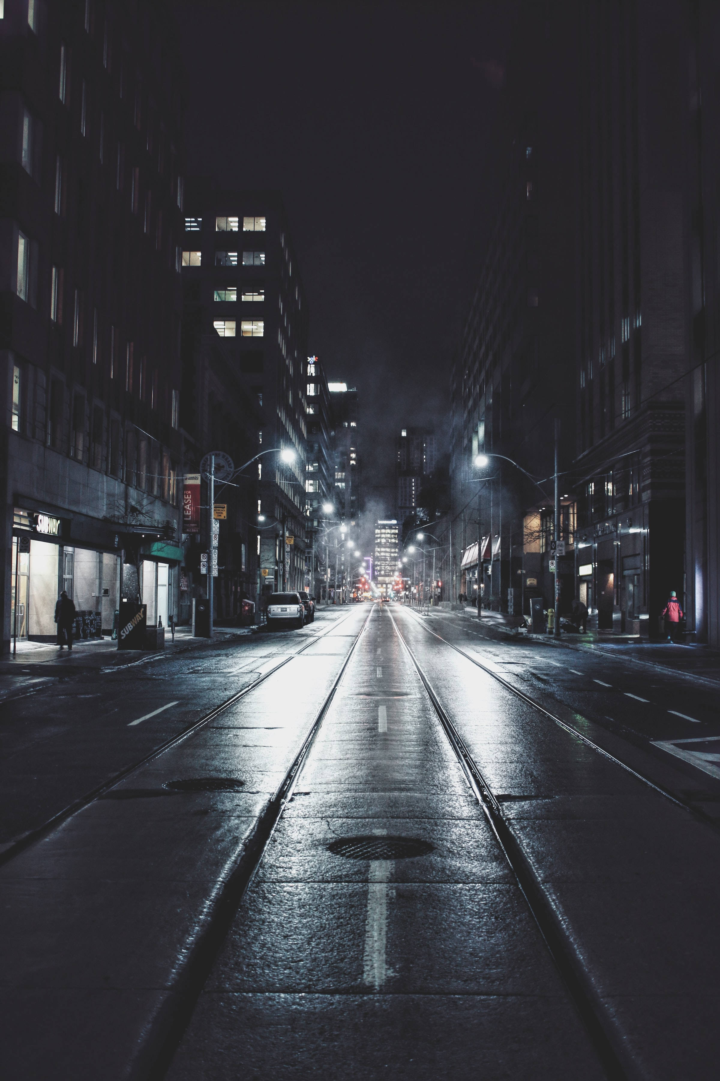 Night Aesthetic 桌布 壁紙 — 夜晚濕漉漉的城市街道反射著街燈和建築物窗戶，營造出陰鬱的城市峽谷效果。