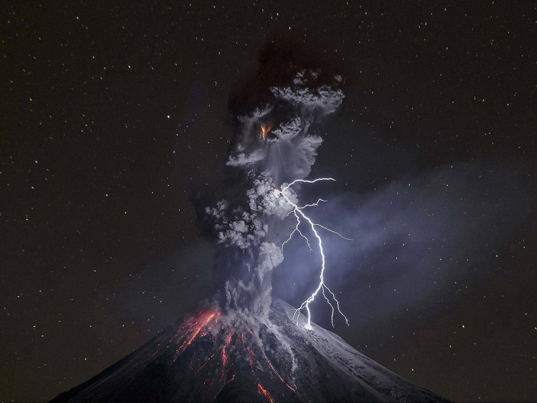National Geographic Desktop 桌布 壁紙 — 夜晚火山爆發，熔岩發光，閃電穿過火山灰雲，星空下。