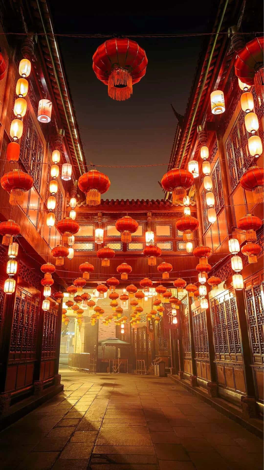 桌布 壁紙 — 夜晚狹窄的傳統小巷，由懸掛在木建築之間的紅色和白色發光燈籠照亮。