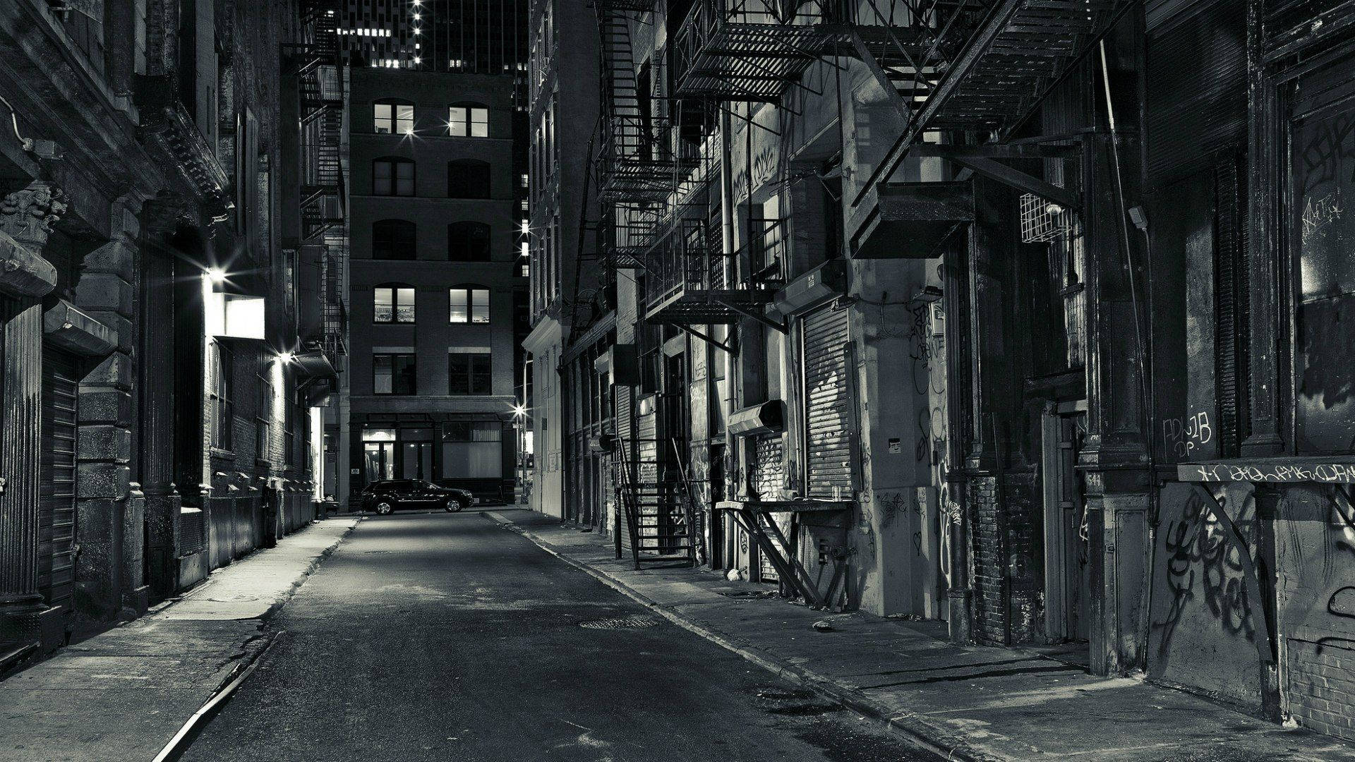  壁紙 — 夜晚狹窄的城市小巷，牆上佈滿塗鴉，街燈下的逃生樓梯。