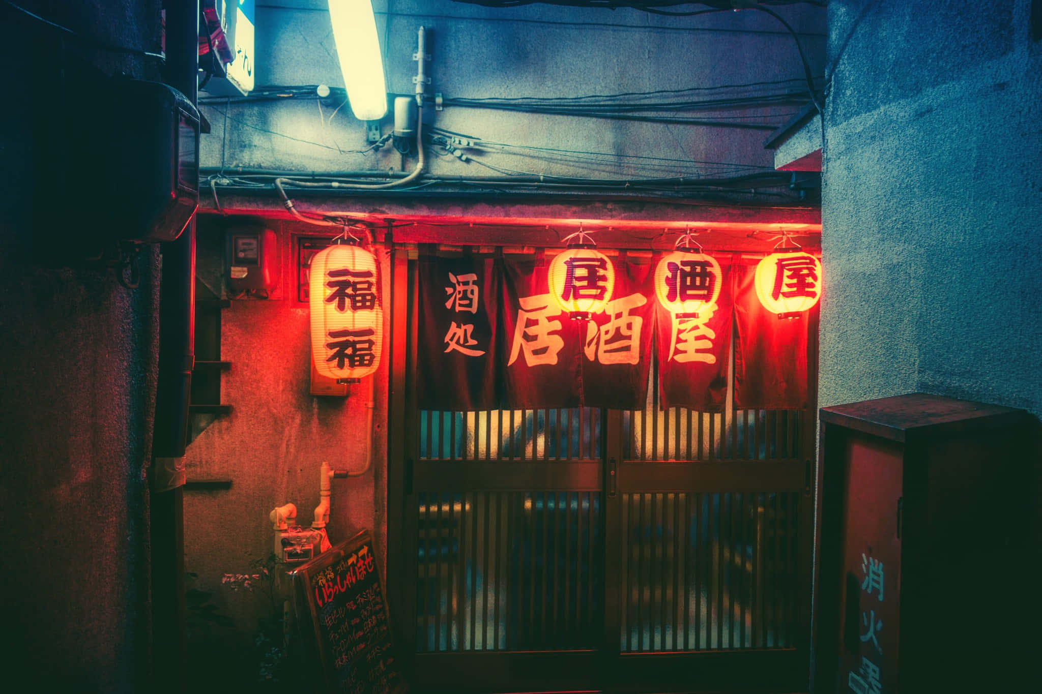 桌布 壁紙 — 夜晚狹窄的小巷，被傳統日本居酒屋入口上方發光的紅色霓虹燈籠和招牌照亮。