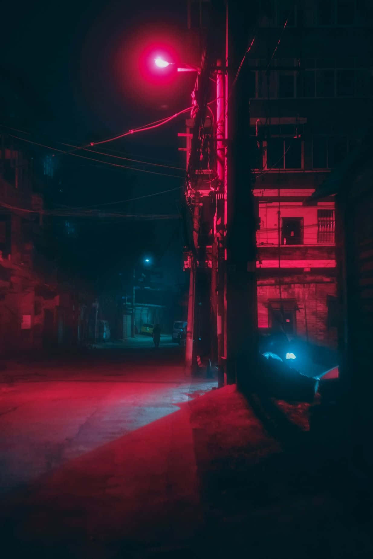 Alleyway 桌布 壁紙 — 夜晚狹窄的小巷被街燈詭異的紅光照亮，在風化的建築物上投下長長的陰影。