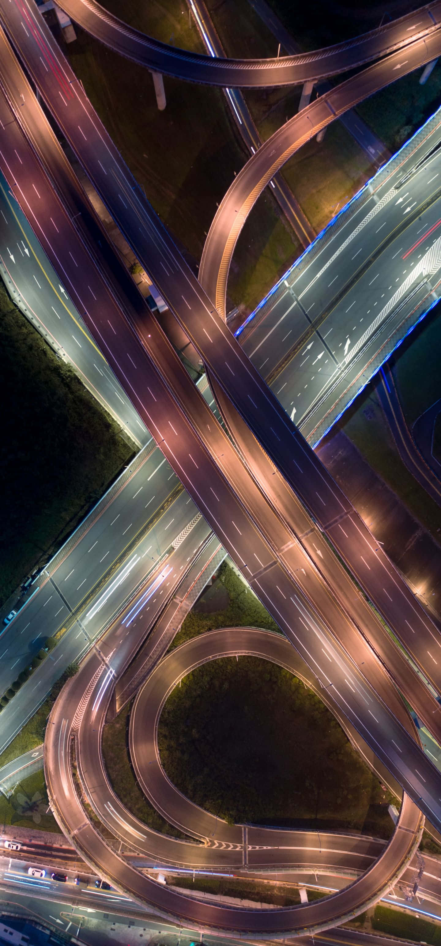 1440x3088 桌布 壁紙 — 夜晚發光的高速公路交流道的空拍圖，有彎曲的道路和拖曳的車燈。