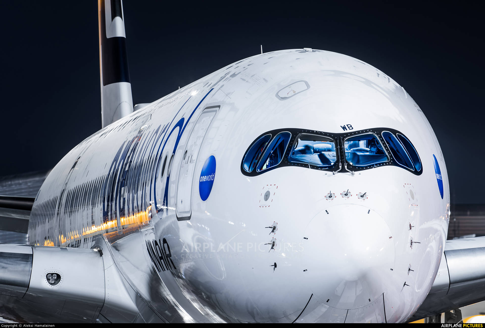 飛機 桌布 壁紙 — 夜晚白色空中巴士A380飛機機頭的近距離特寫，藍色駕駛艙窗戶和照亮的地面燈光反射在機身上。
