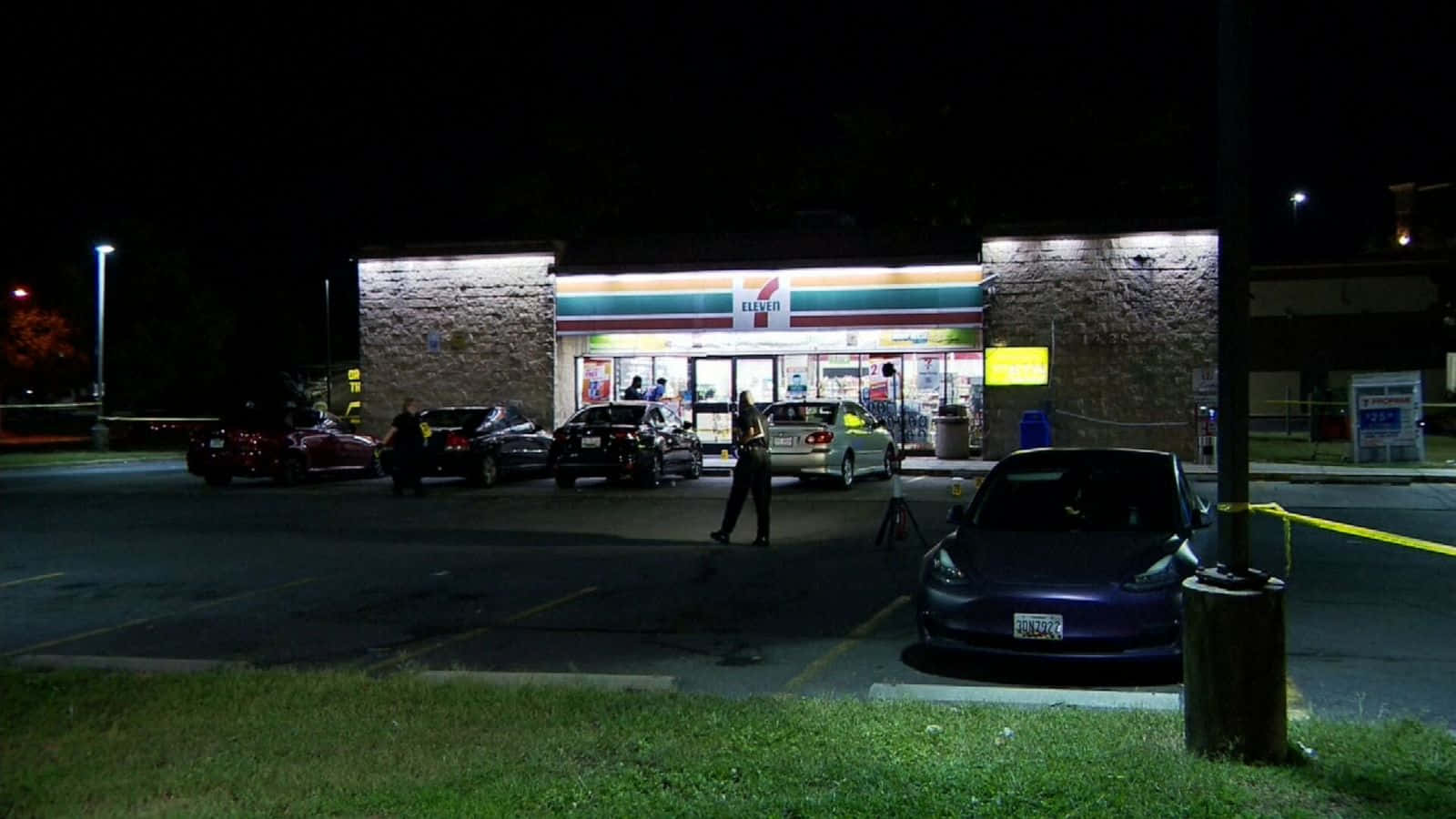 7-ELEVEN 桌布 壁紙 — 夜晚的7-Eleven商店，警車和警員包圍著用黃色膠帶封鎖的區域。