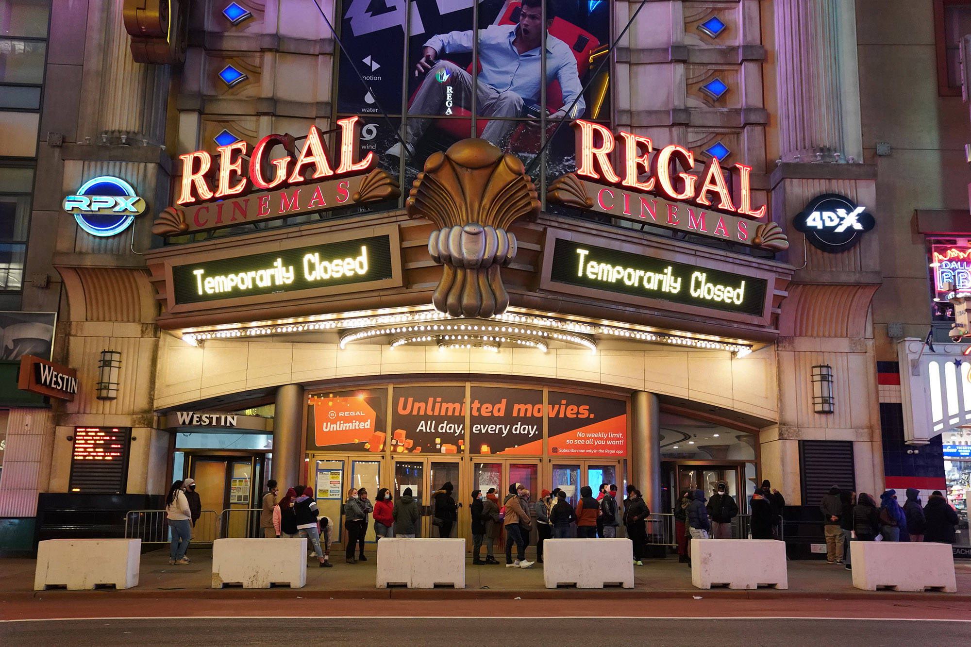 Regal 桌布 壁紙 — 夜晚的Regal Cinemas戲院，發光的霓虹招牌和人群在明亮燈光下聚集在外面。
