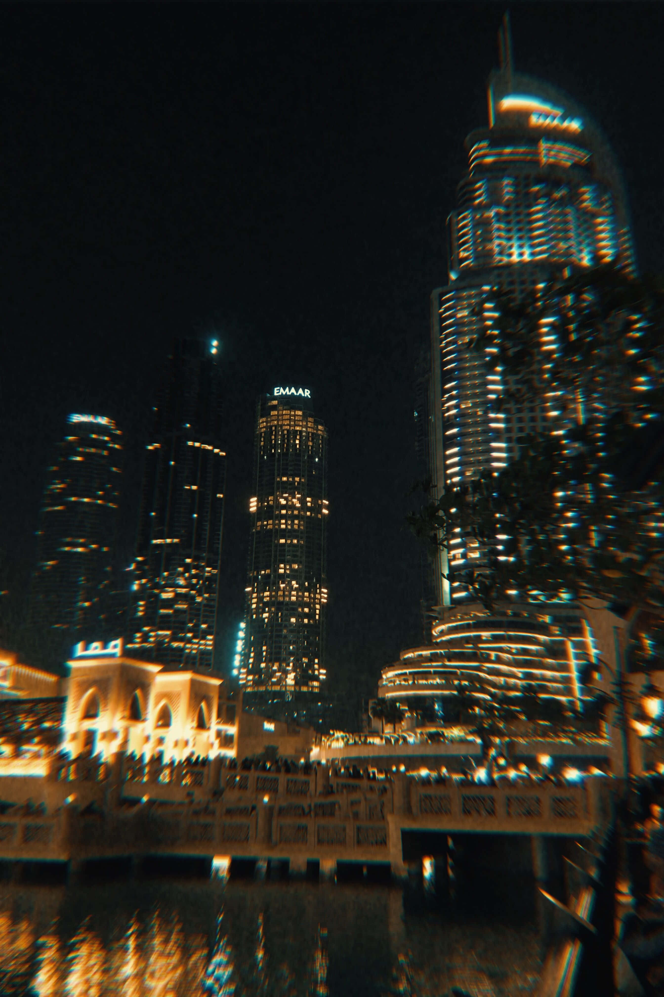Life Aesthetic 桌布 壁紙 — 夜晚的城市景觀，摩天大樓在黑暗的天空下在水面上反射出光芒。
