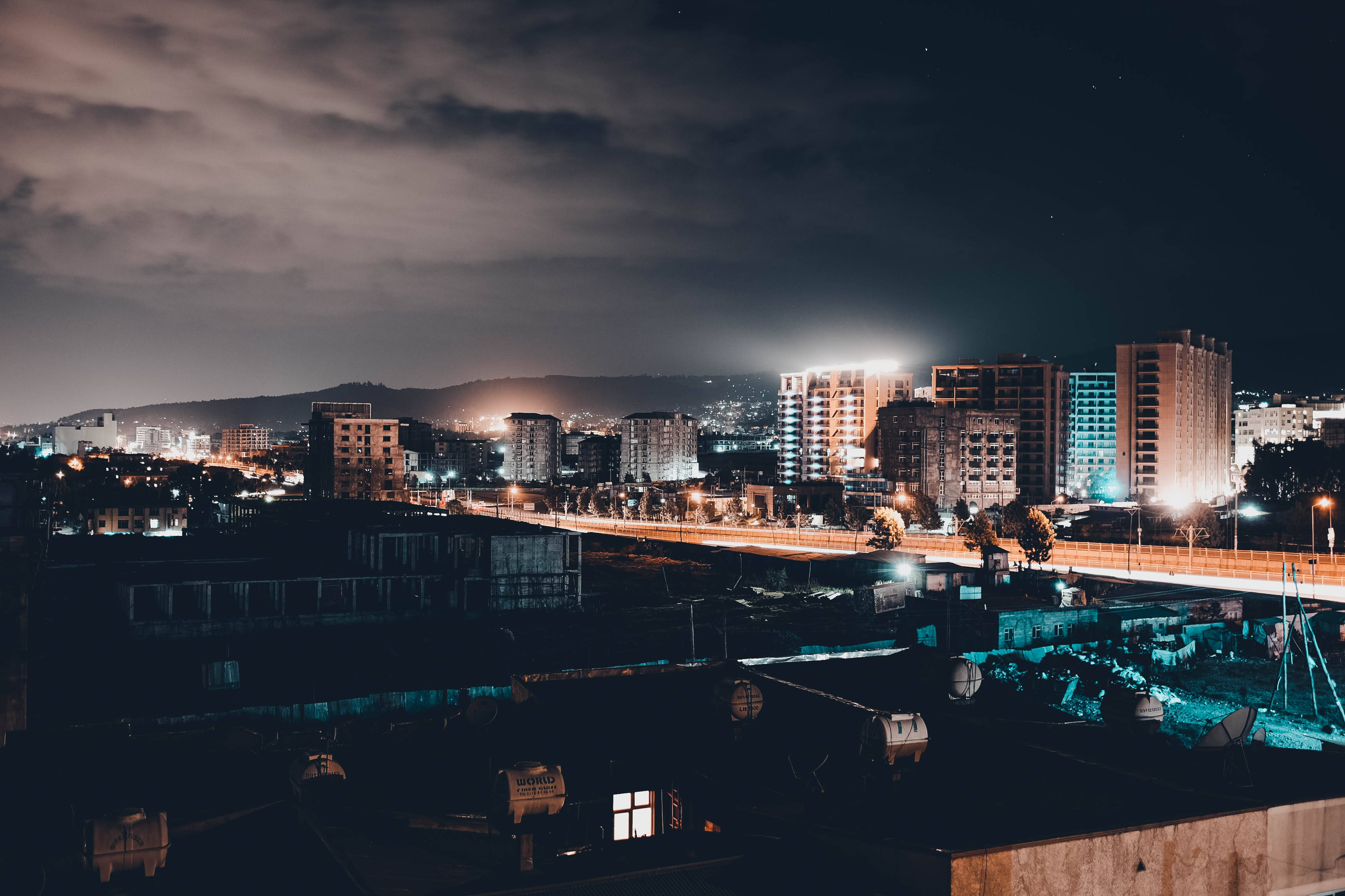 Ethiopia 桌布 壁紙 — 夜晚的城市景觀，發光的建築物和一座亮燈的橋樑，天空多雲。