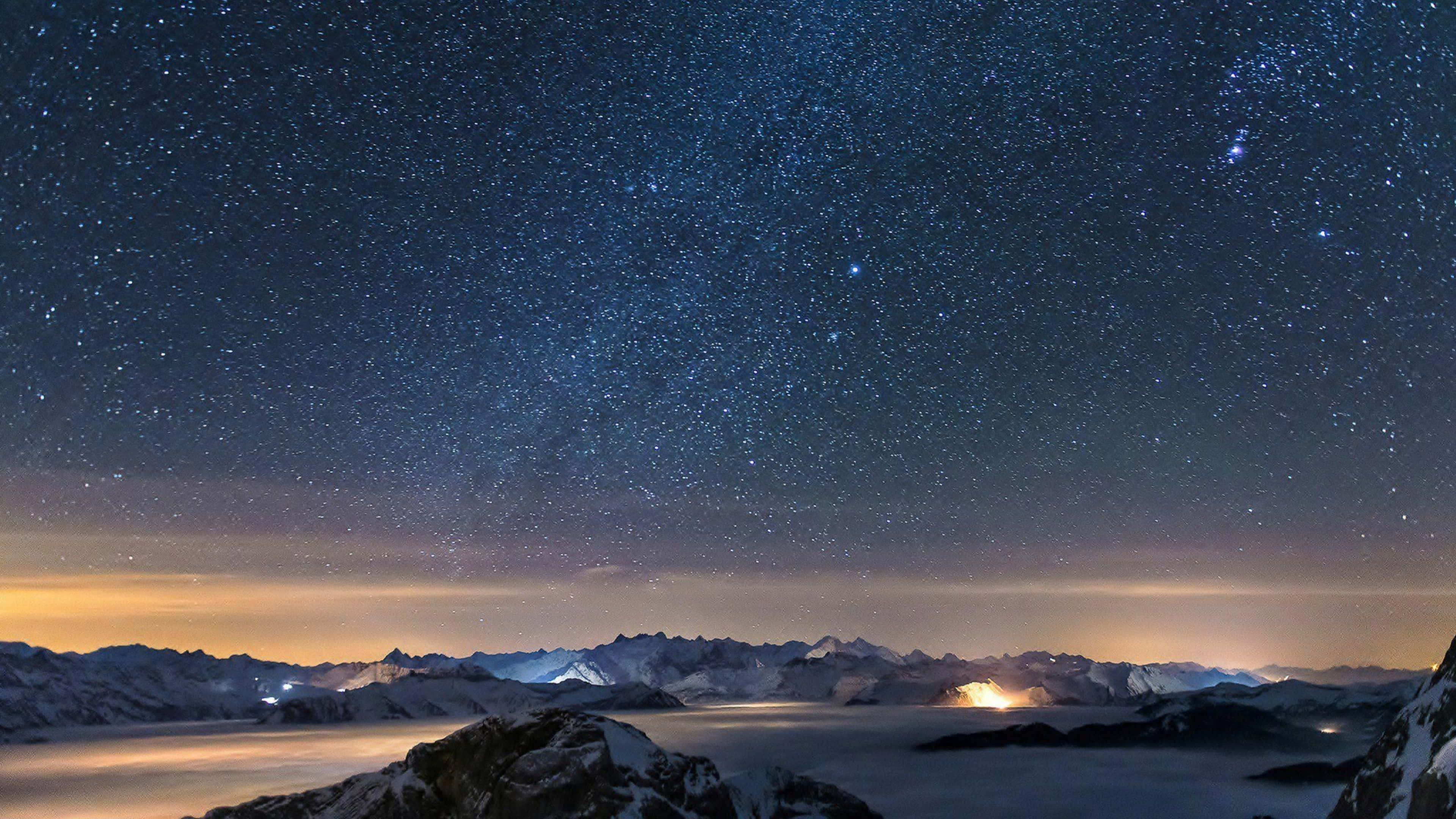 夜晚的天空，雲層與星辰高聳於山巒之上 壁紙