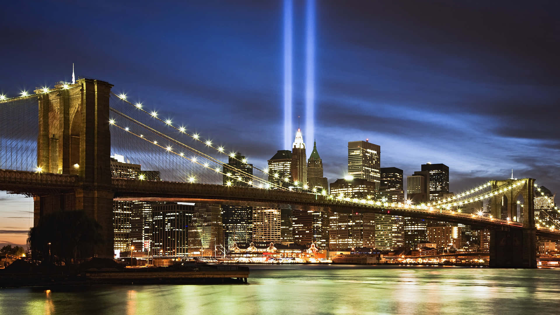 New York 桌布 壁紙 — 夜晚的布魯克林大橋，Tribute in Light 光束刺穿曼哈頓天際線上的天空，倒映在水中。