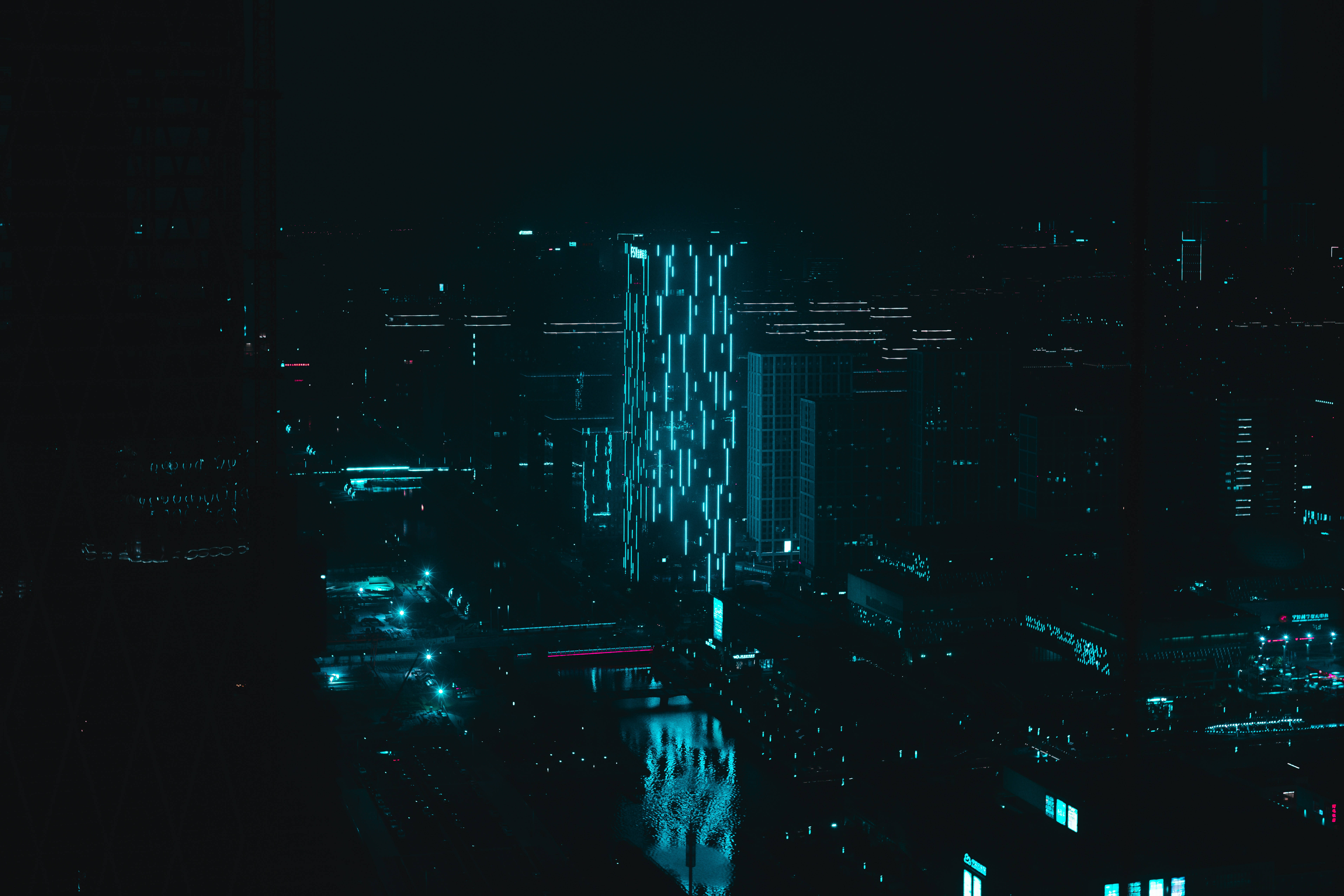 霓虹藍動畫 桌布 壁紙 — 夜晚的未來城市景觀，由一座高聳的摩天大樓主導，散發著垂直的藍色燈光圖案。