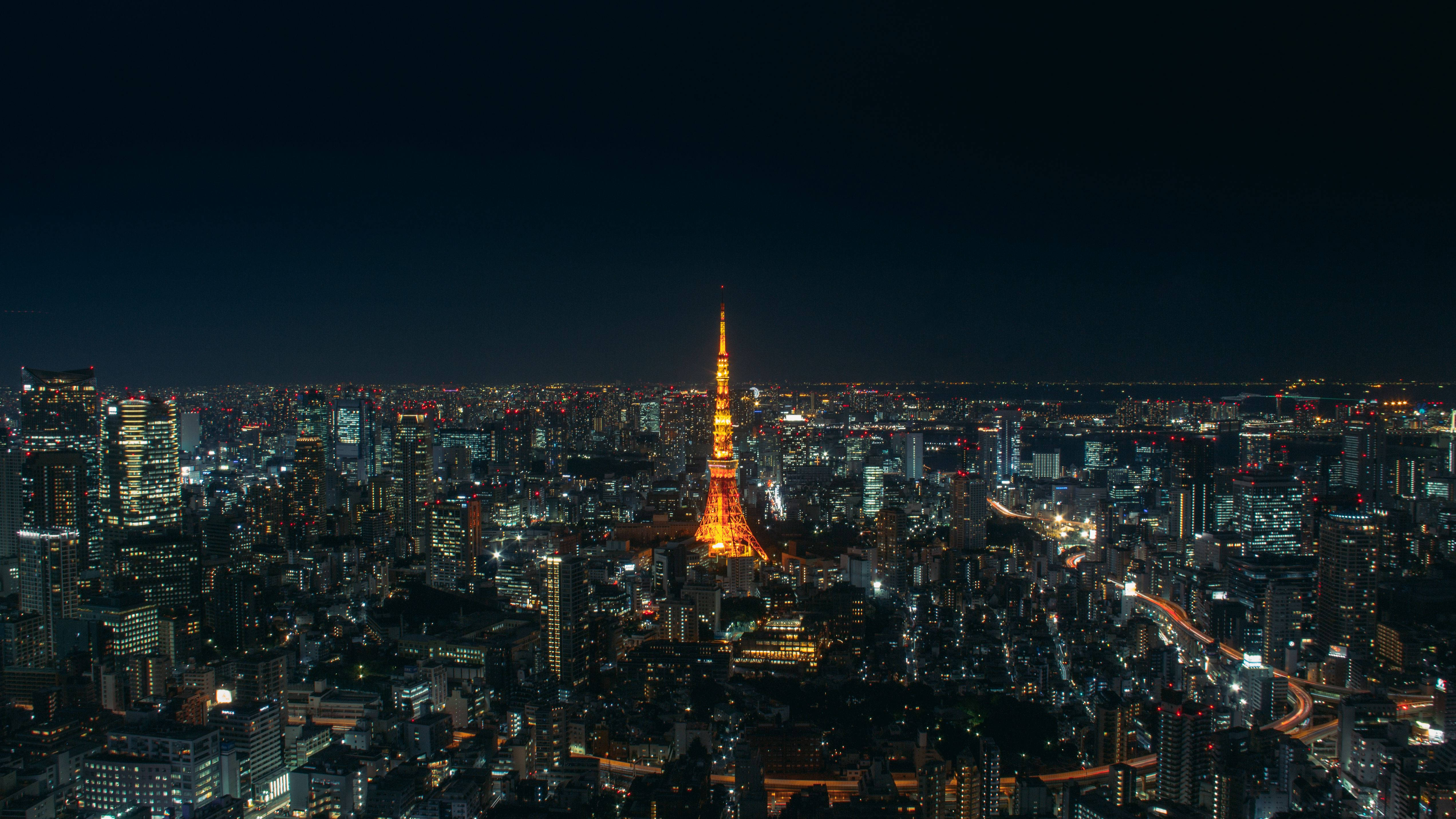 日本 桌布 壁紙 — 夜晚的東京天際線，明亮的東京塔在閃爍的摩天大樓和蜿蜒的道路中高聳入雲。
